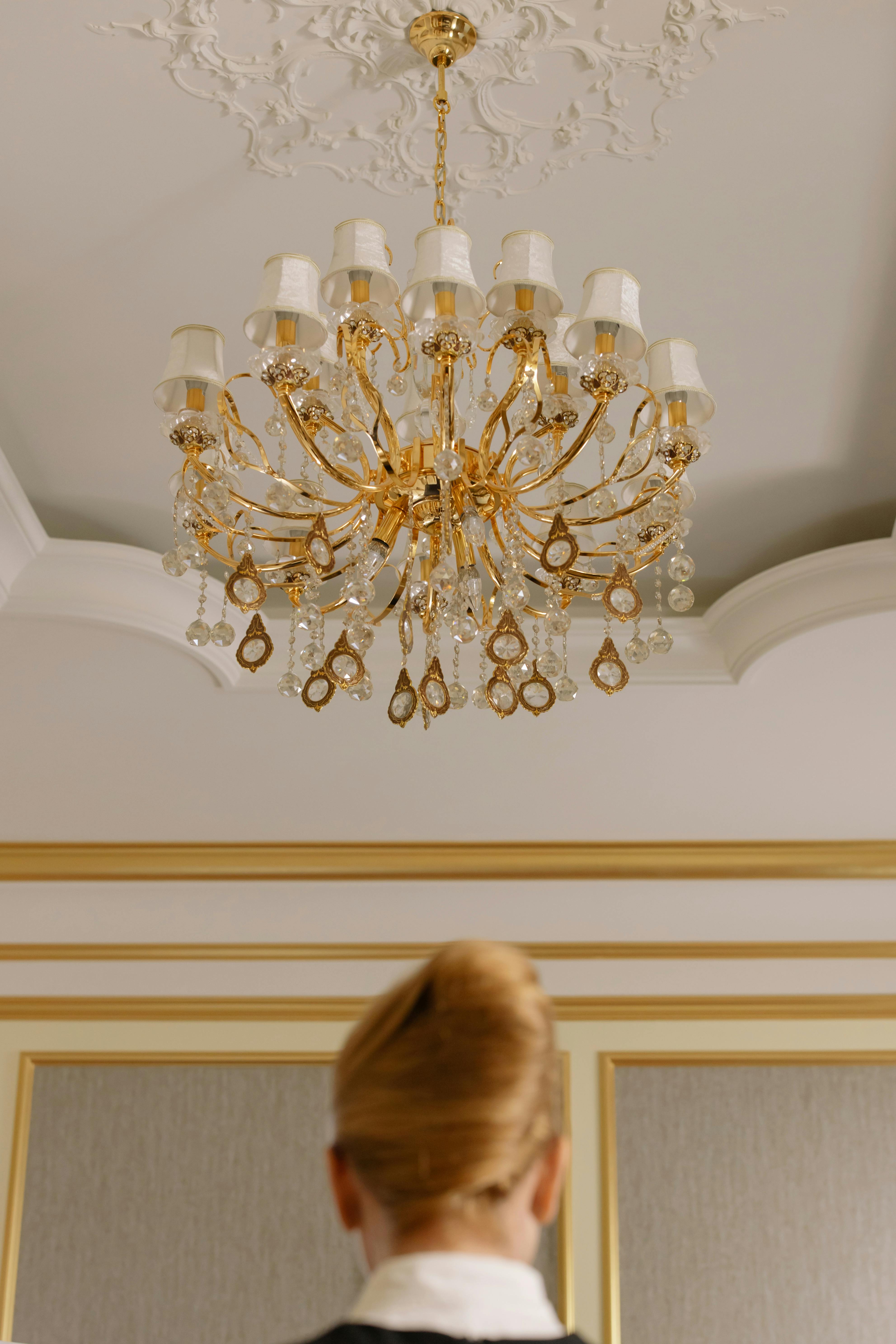 Femme debout sous le lustre d'une chambre d'hôtel | Source : Pexels