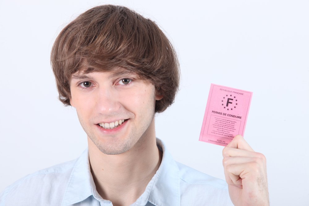 Un jeune homme montrant son permis de conduire français. | Shutterstock 