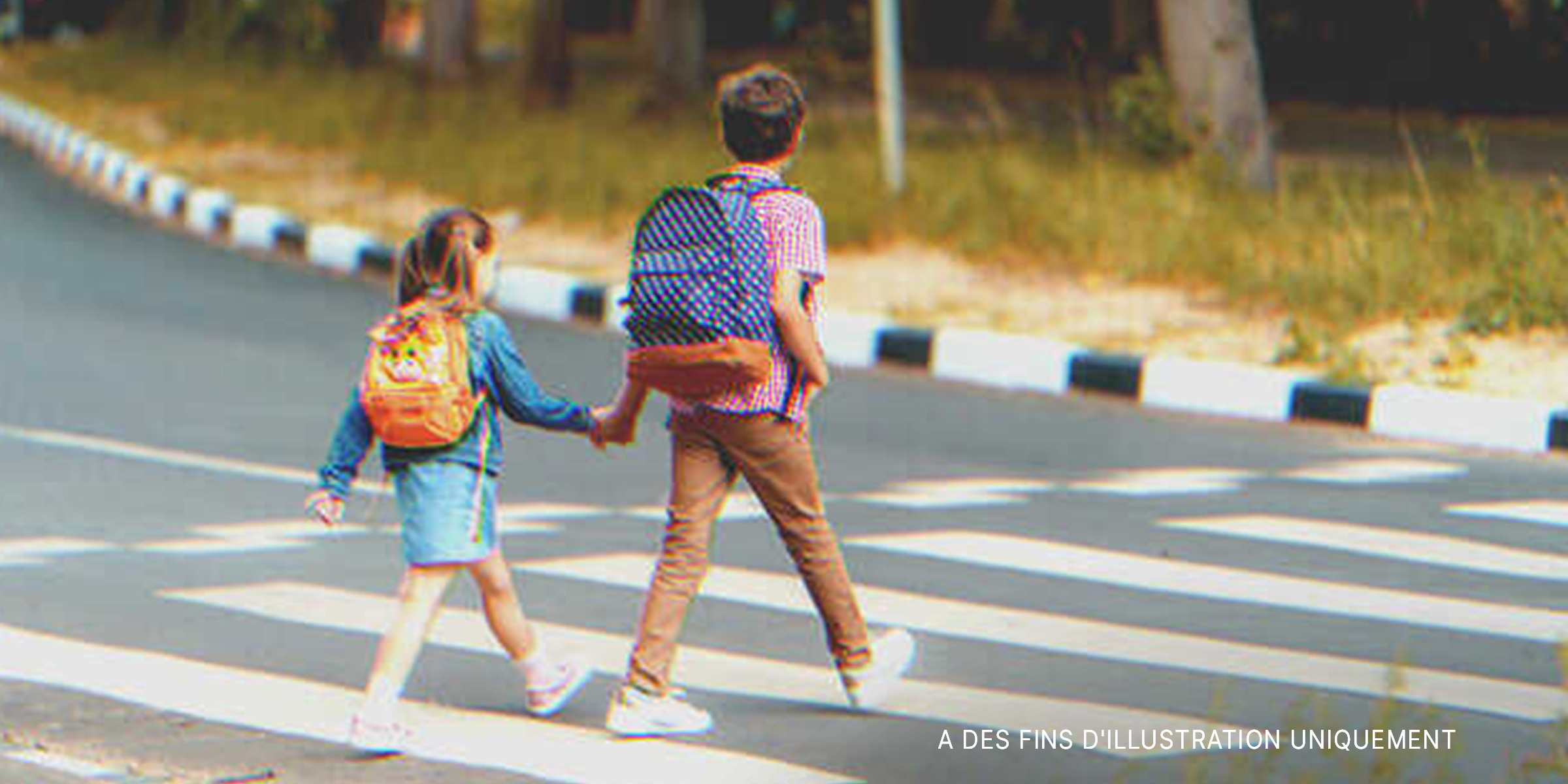 Un garçon marchant dans la rue en tenant la main d'une petite fille | Source : Shutterstock