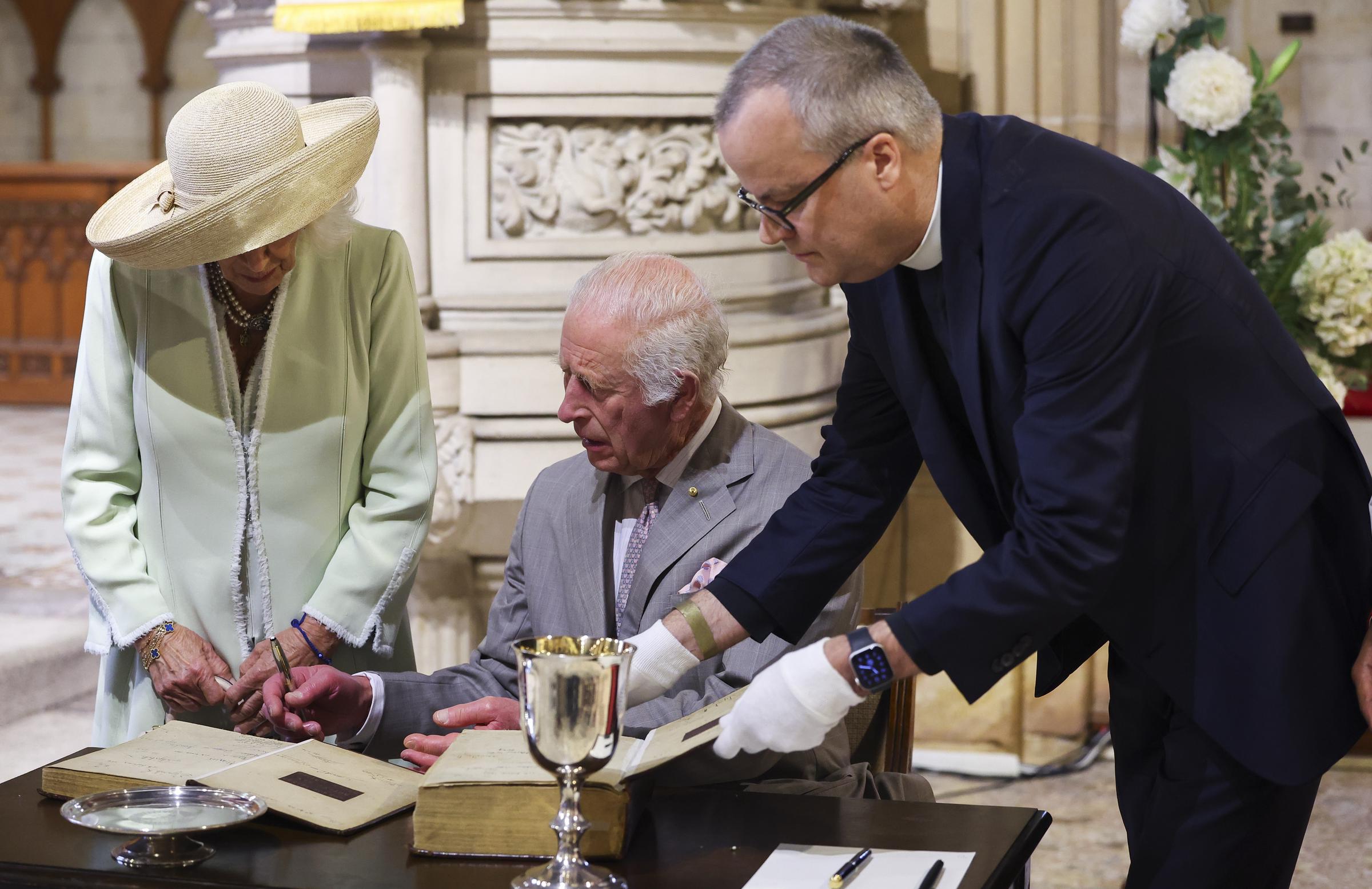 Le roi Charles III et la reine Camilla regardent le livre de la prière commune lors d'une visite à l'église anglicane St. Thomas, le 20 octobre 2024, à Sydney, en Australie. | Source : Getty Images