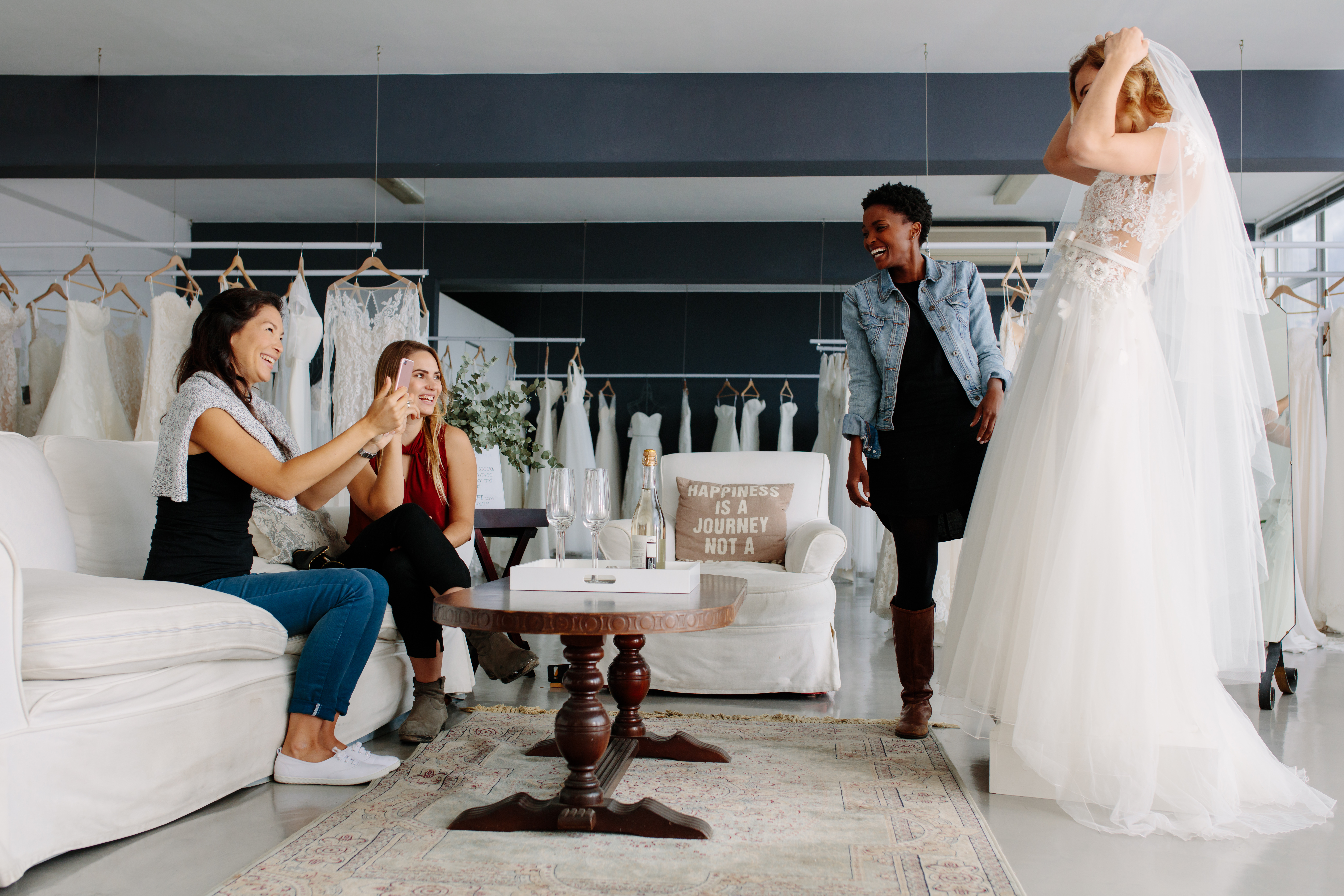 Une femme essayant une robe de mariée entourée de ses amies | Source : Shutterstock