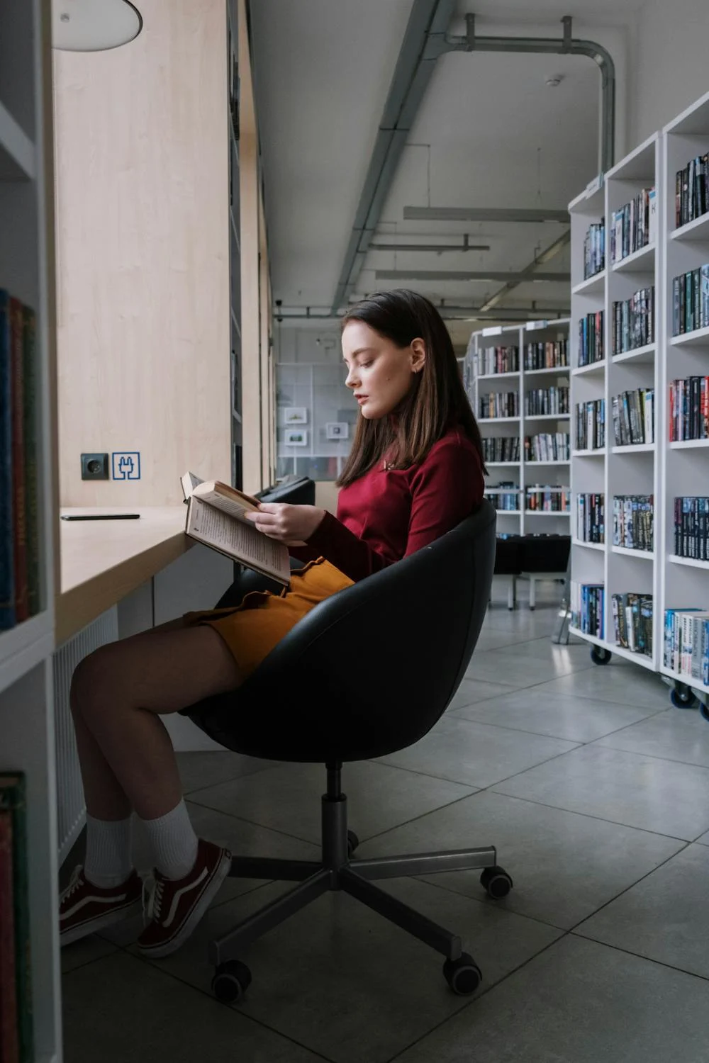 Une femme lisant dans une bibliothèque | Source : Pexels