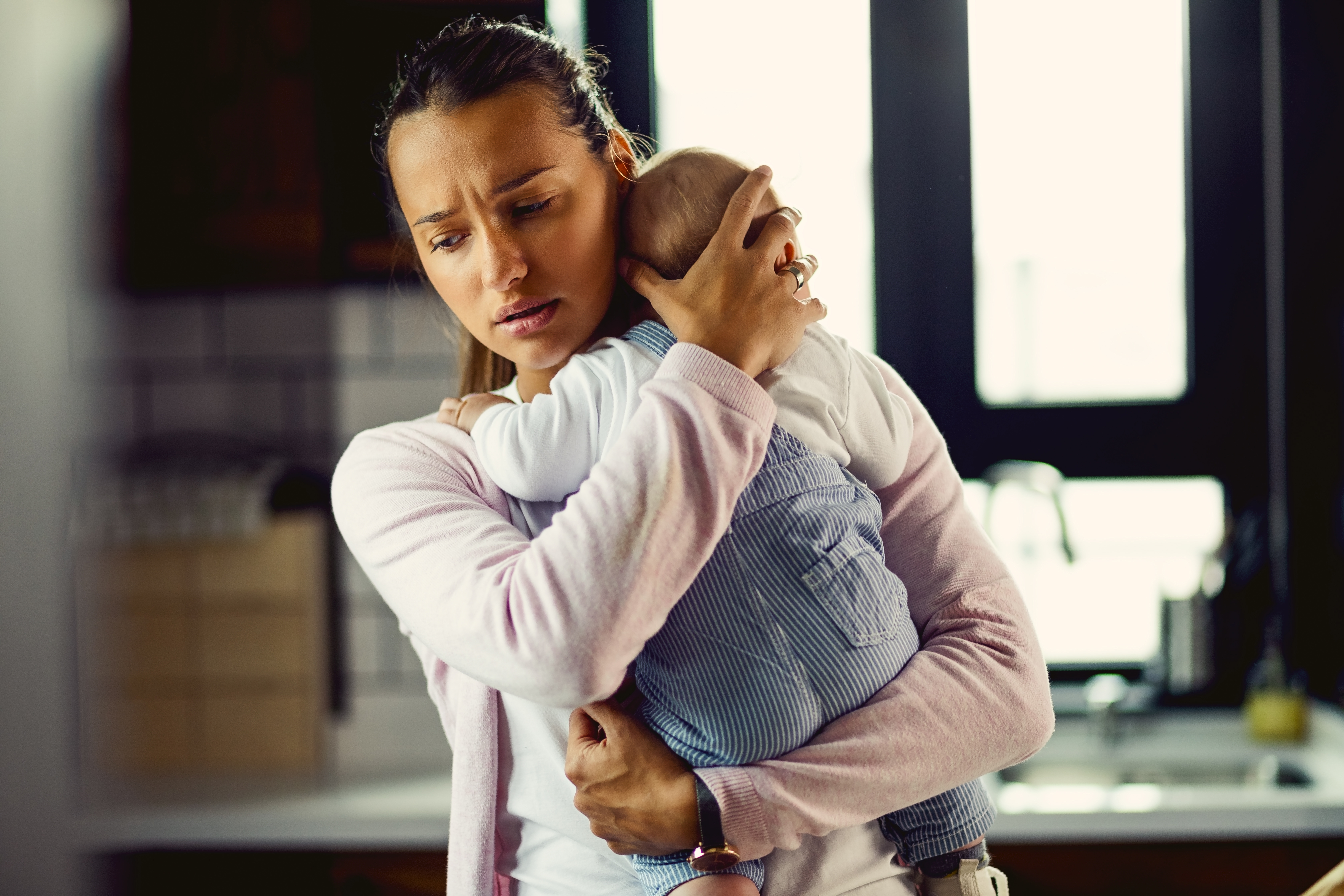 Mujer joven con un bebé en brazos. | Fuente: Shutterstock