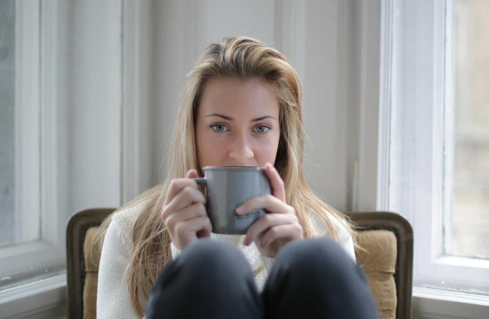 Une femme assise sur une chaise tout en tenant une tasse à café | Source : Pexels