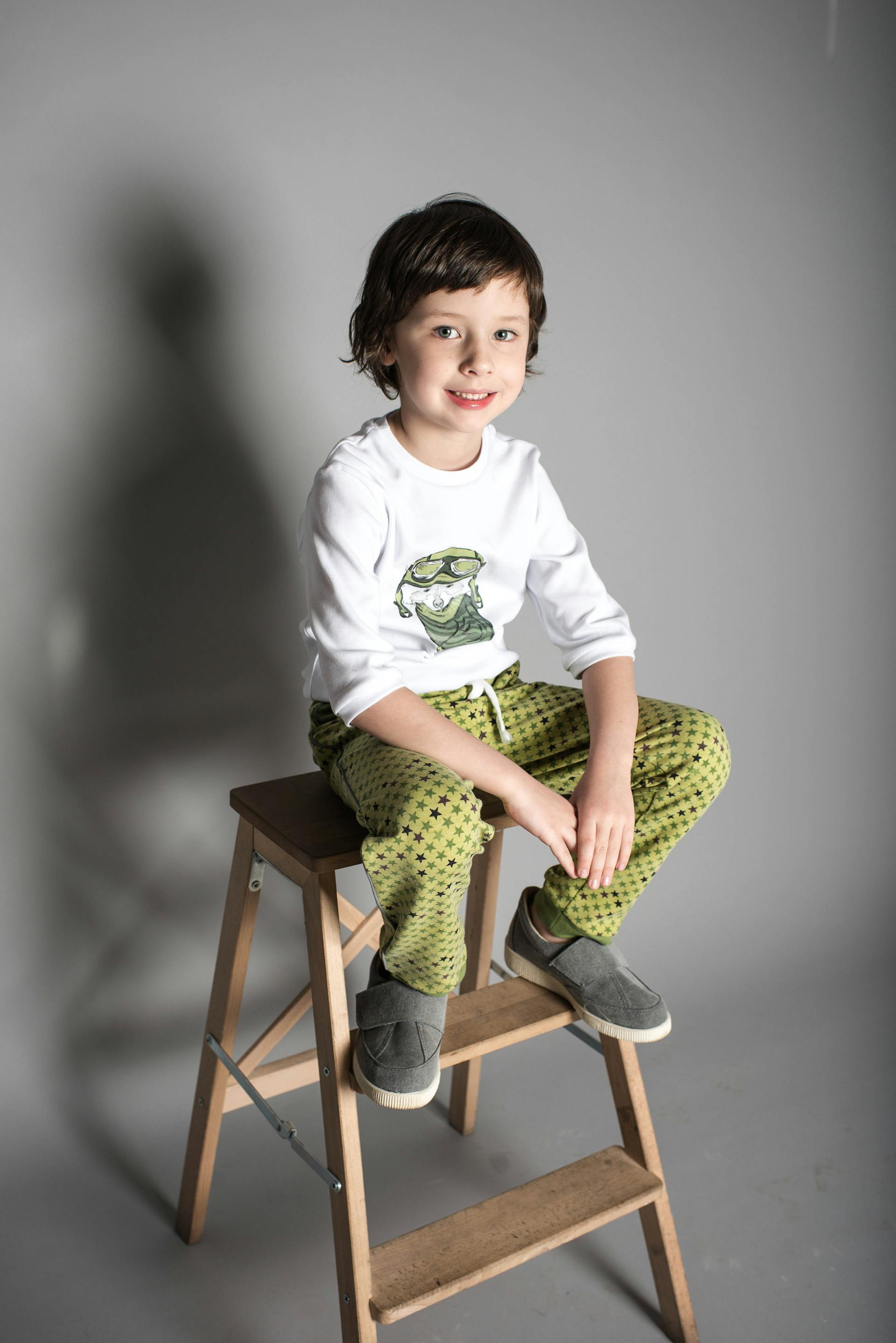 Un petit garçon souriant assis sur un tabouret | Source : Pexels