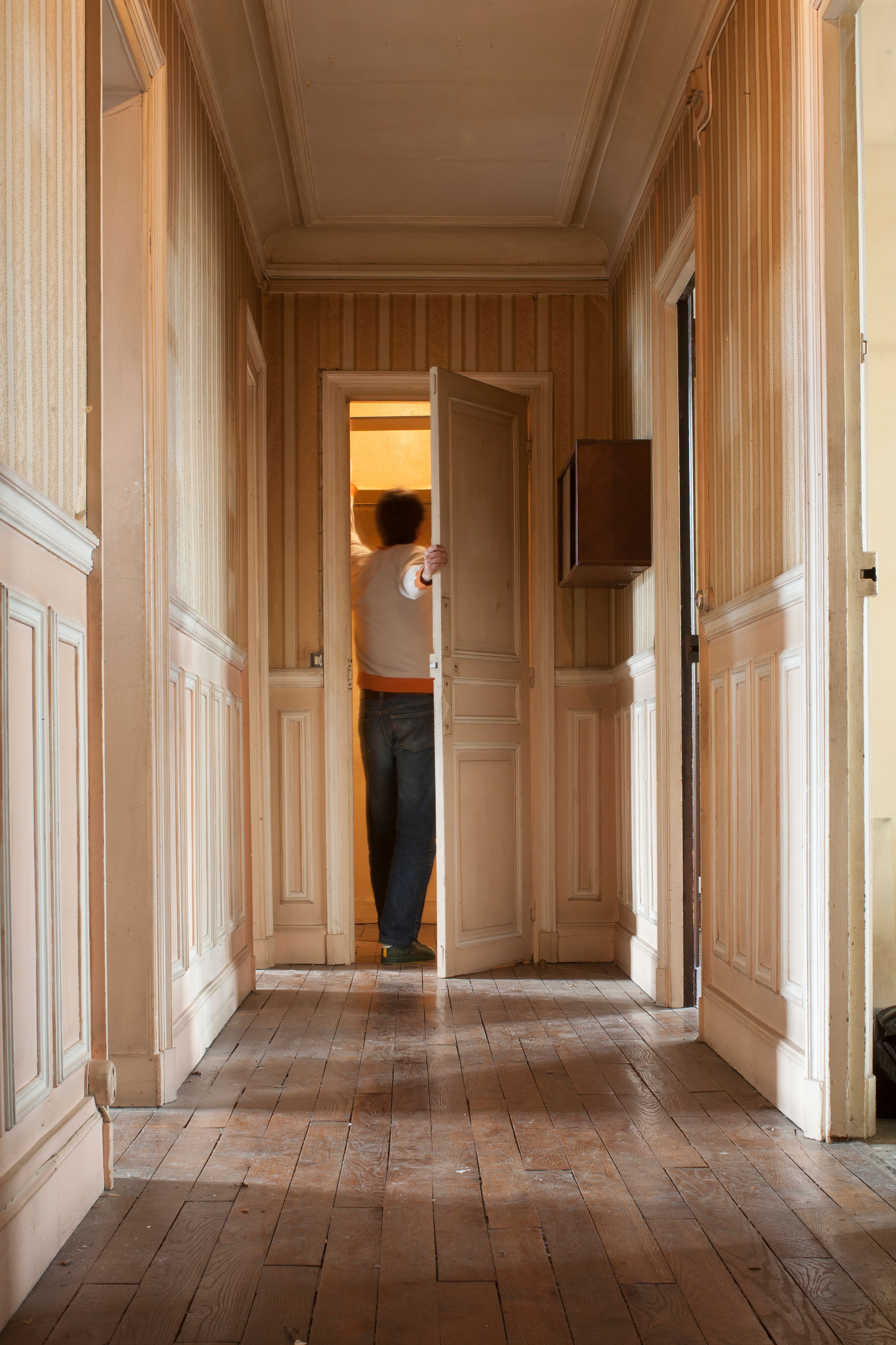 Un homme ouvre une porte au bout d'un couloir. | Source : Getty Images