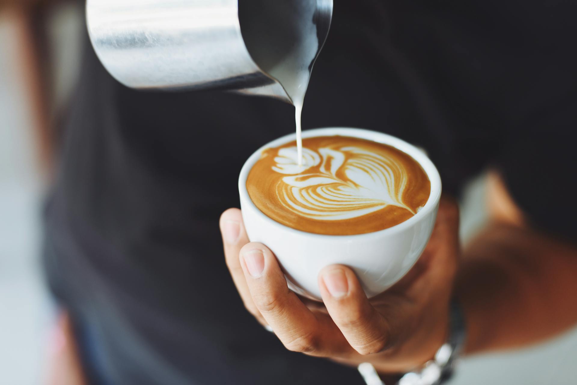 Un homme verse de la crème dans une tasse de café | Source : Pexels