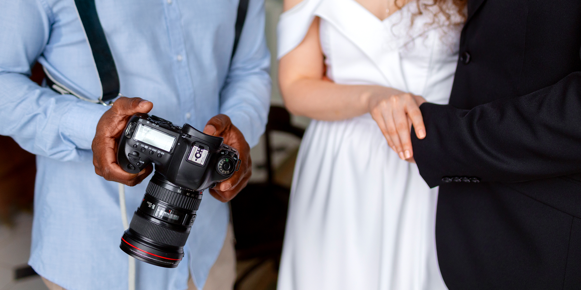 Un homme tenant un appareil photo à côté d'un couple de mariés | Source : Freepik