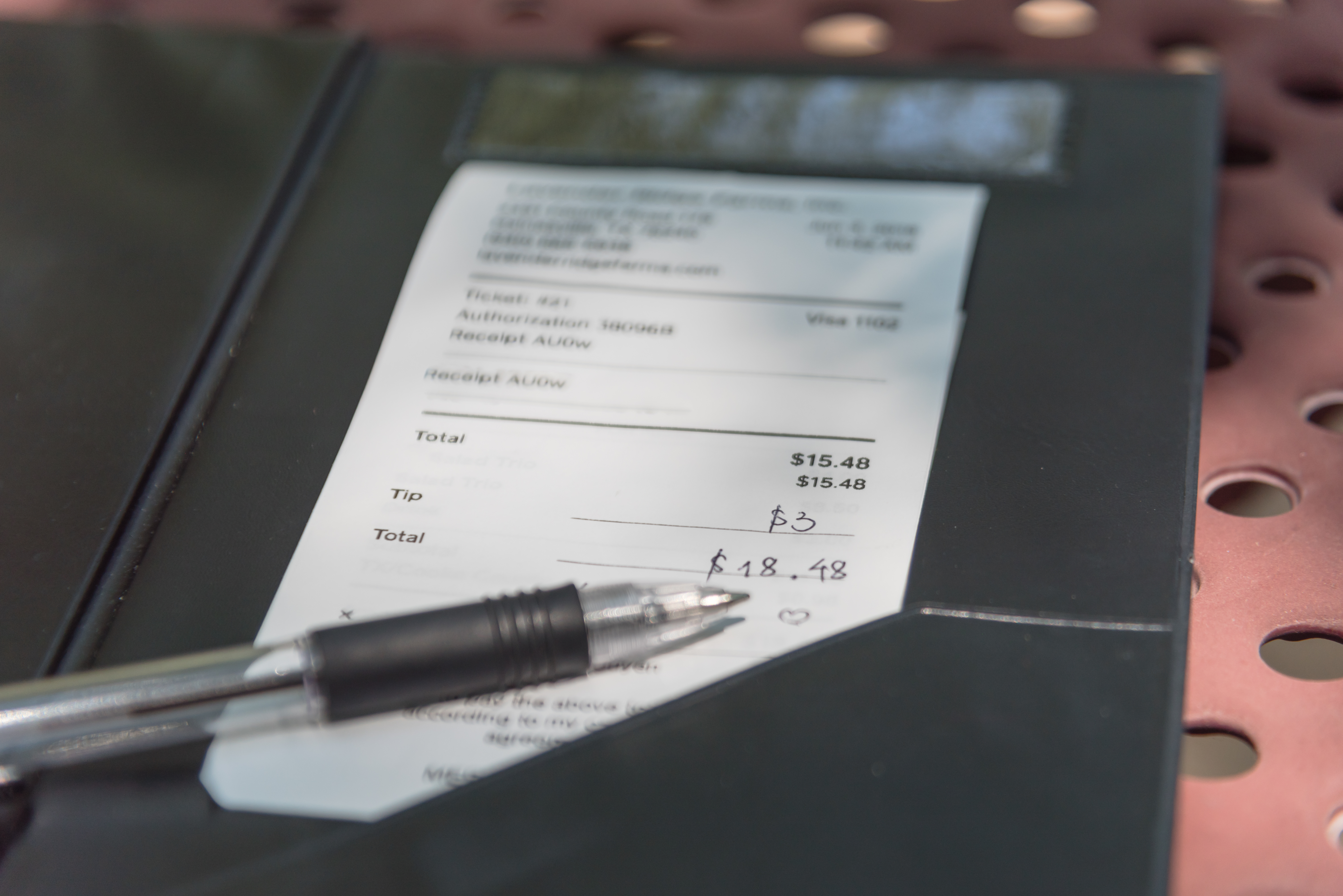 Porte-billets en cuir ouvert avec un chèque de restaurant et un stylo | Source : Shutterstock