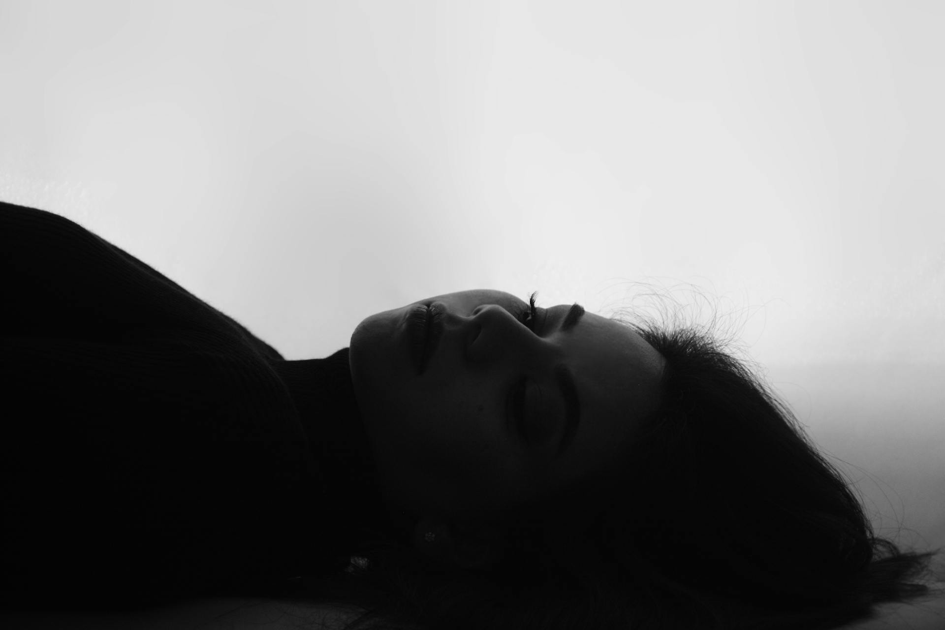 Photo en niveaux de gris d'une femme allongée | Source : Pexels