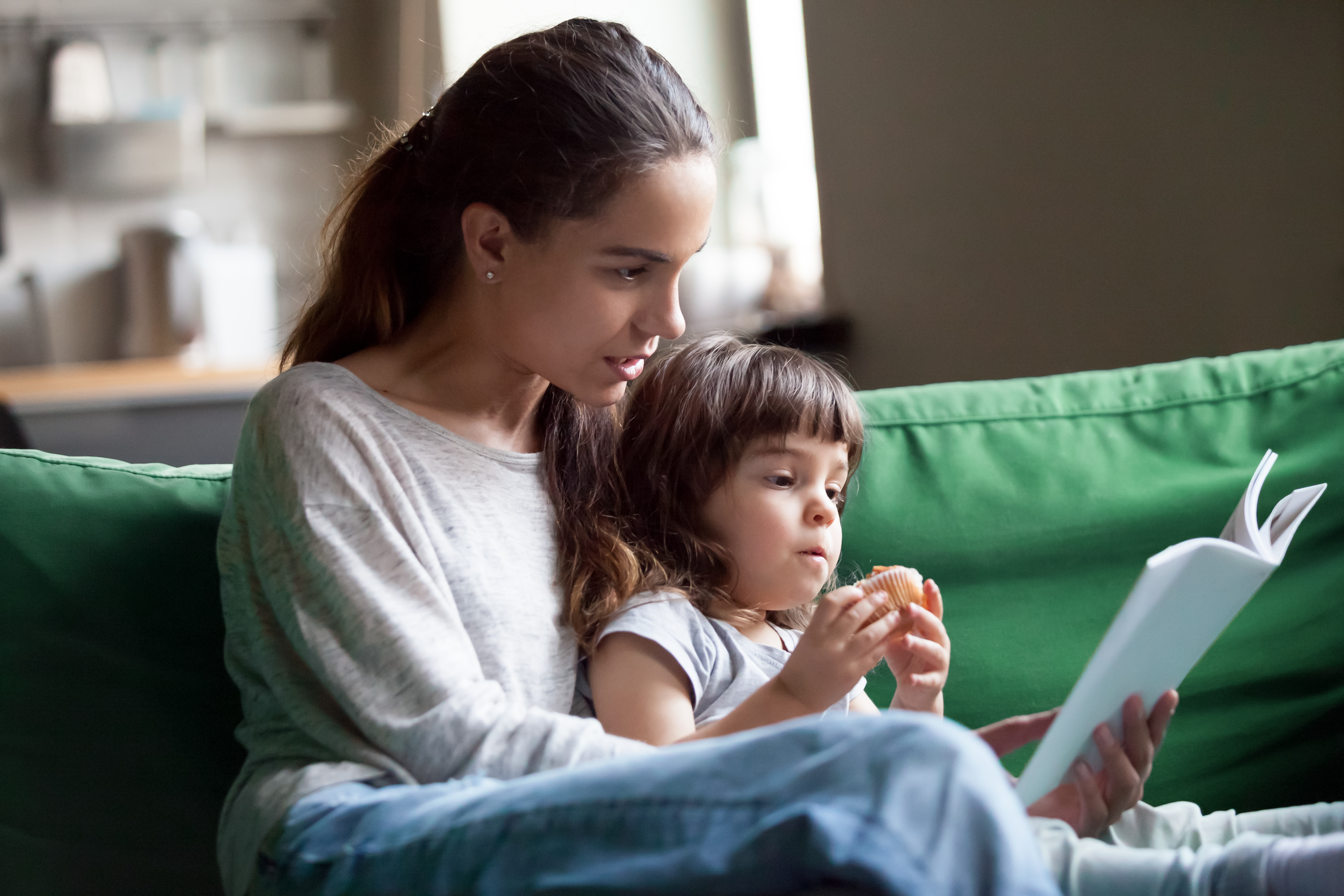 Mulher jovem lendo um livro com uma menina | Fonte: Shutterstock