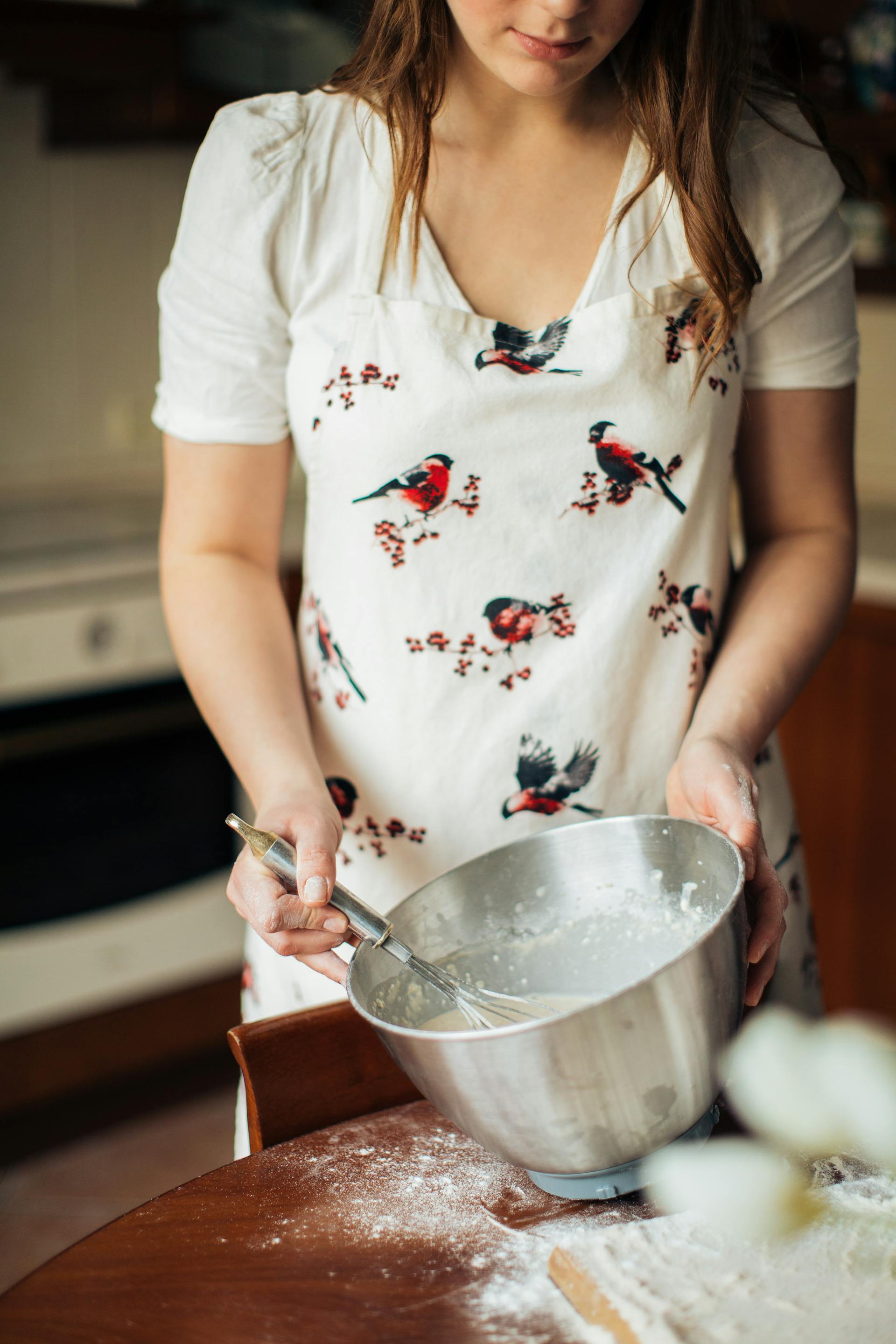 Gros plan d'une jeune femme mélangeant des ingrédients dans un bol en acier inoxydable pour la cuisson au four | Source : Pexels