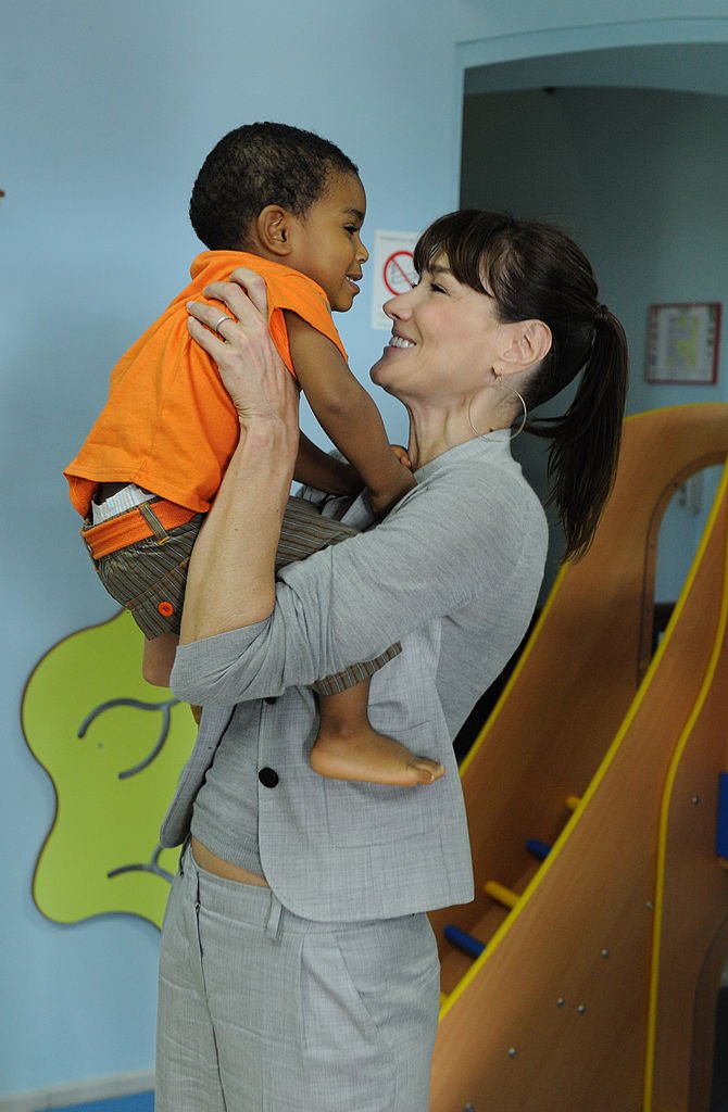 Carla Bruni-Sarkozy joue avec un enfant lors de sa visite à la crèche "Iles aux enfants" du Lamentin, le 8 janvier 2011 en Martinique. І Source : Getty Images