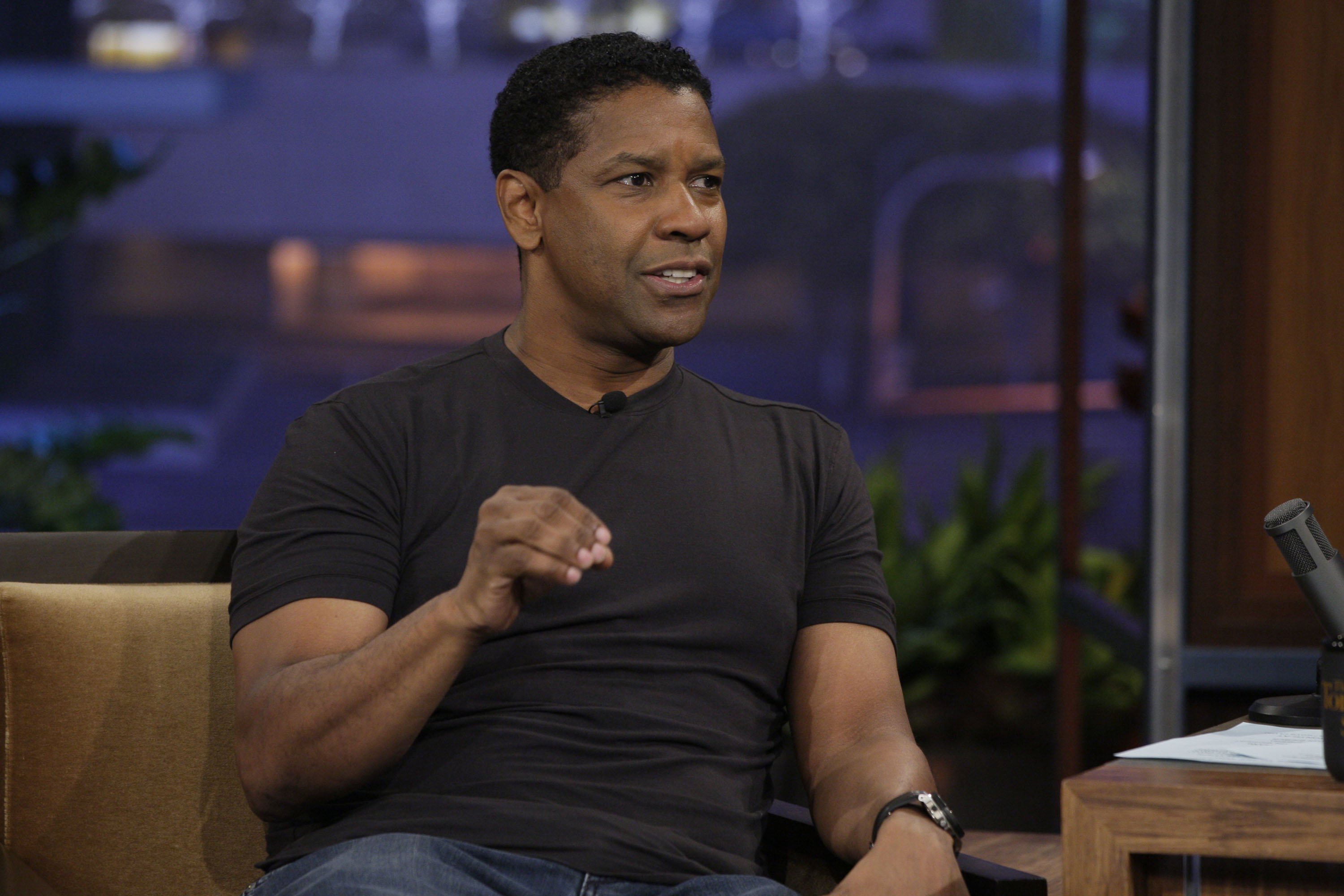 Lors d'une interview dans « The Tonight Show », Denzel Washington apparaît vêtu d'un t-shirt noir ajusté, les cheveux courts et naturellement ondulés. Son style est décontracté mais soigné, reflétant sa confiance en lui après une série de succès au box-office.
