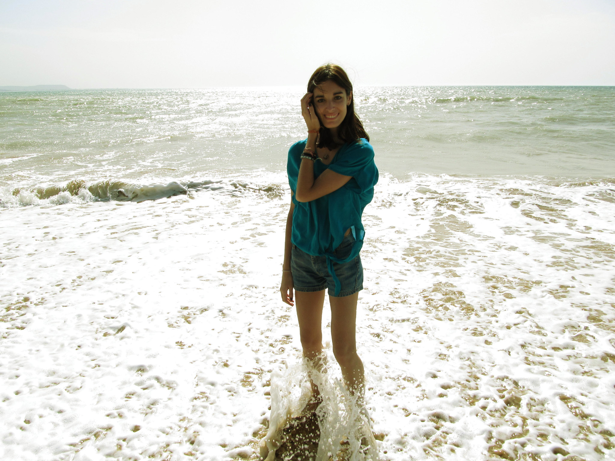 Une jeune femme sourit alors qu'elle se trouve dans l'eau sur une plage | Source : Flickr