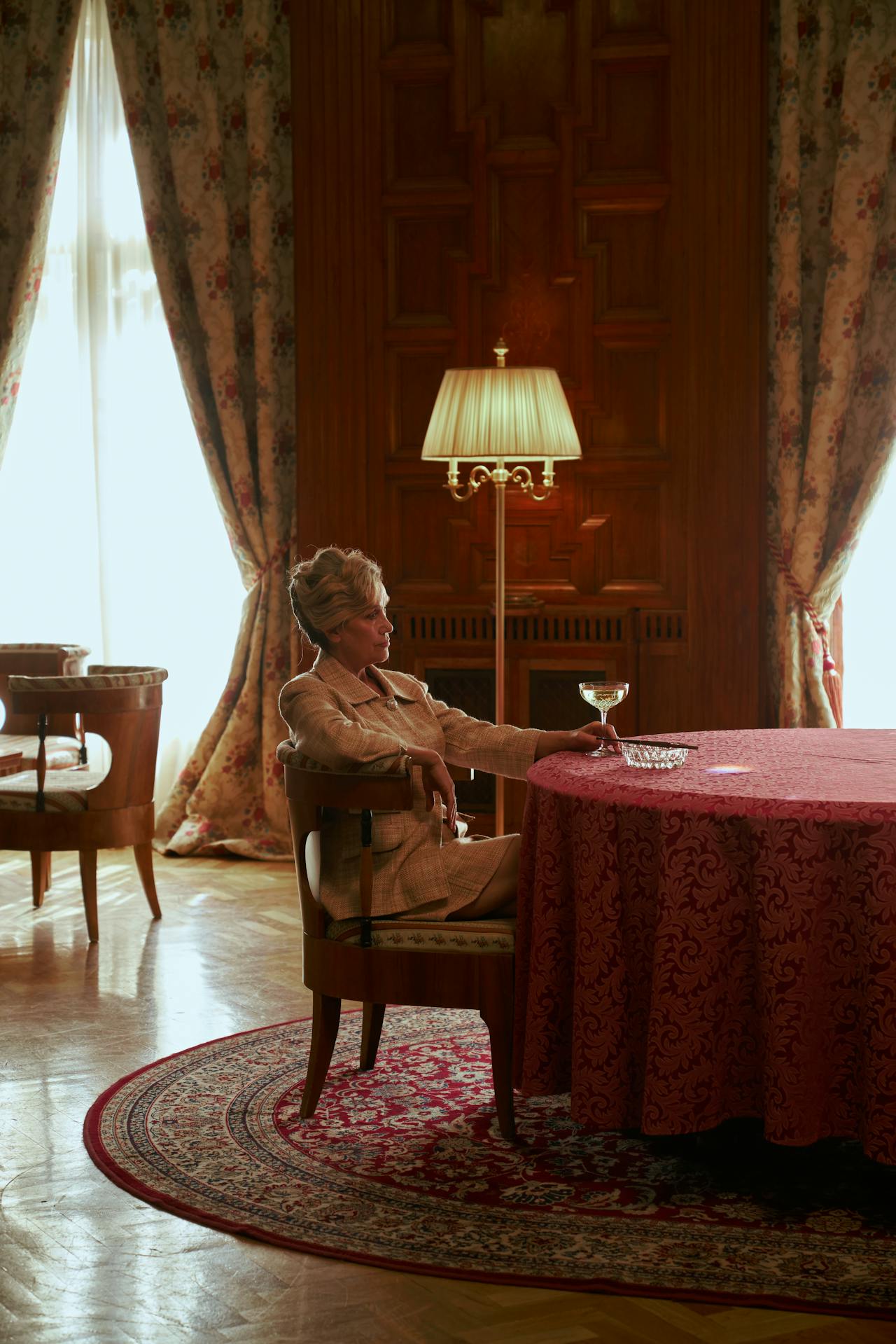 Une élégante femme âgée assise à une table et tenant un verre | Source : Pexels