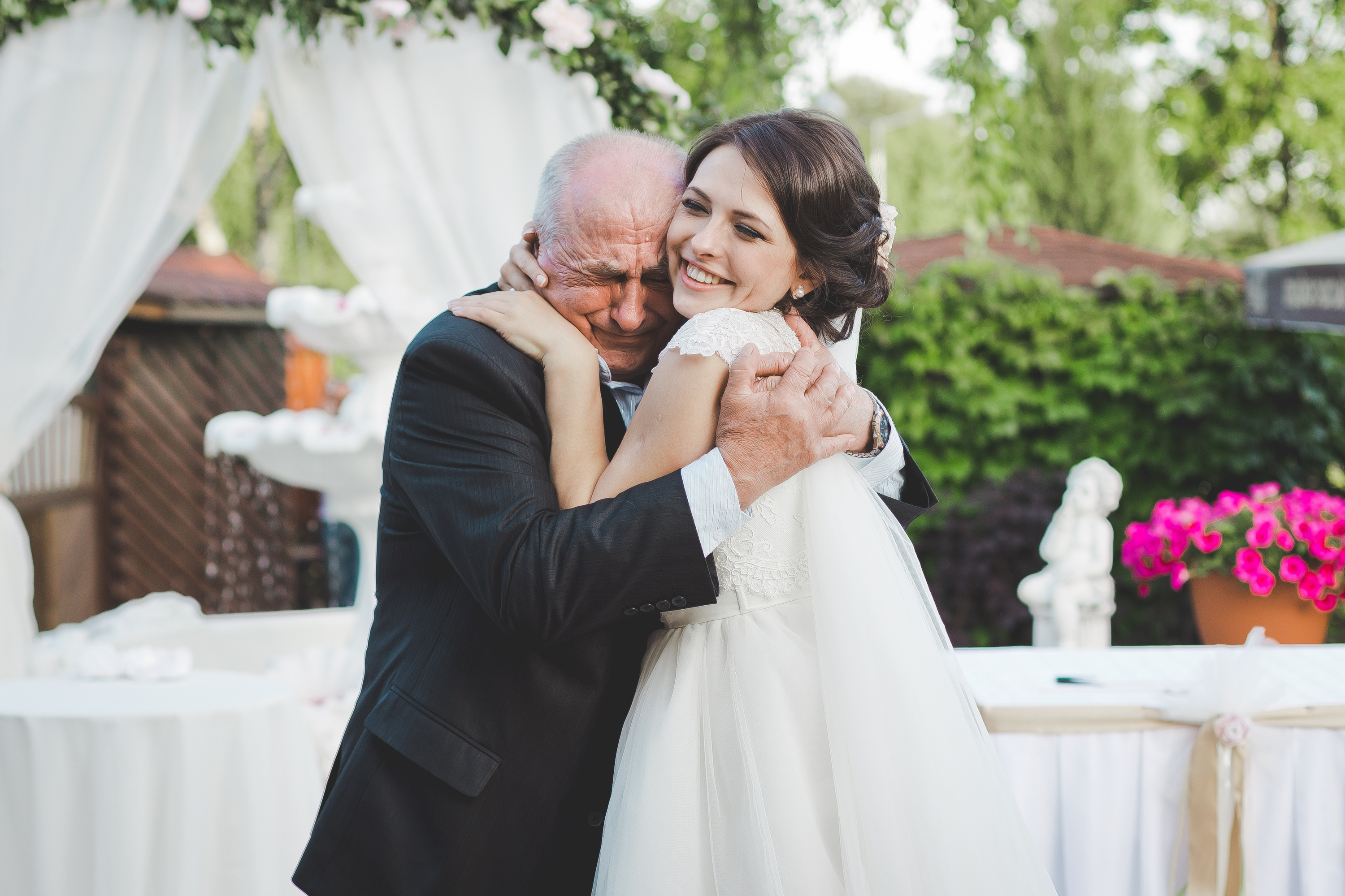 La mariée sourit en serrant un homme plus âgé dans ses bras | Source : Shutterstock