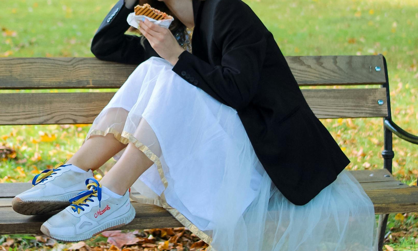 Une femme mangeant un sandwich sur un banc public | Source : Pexels