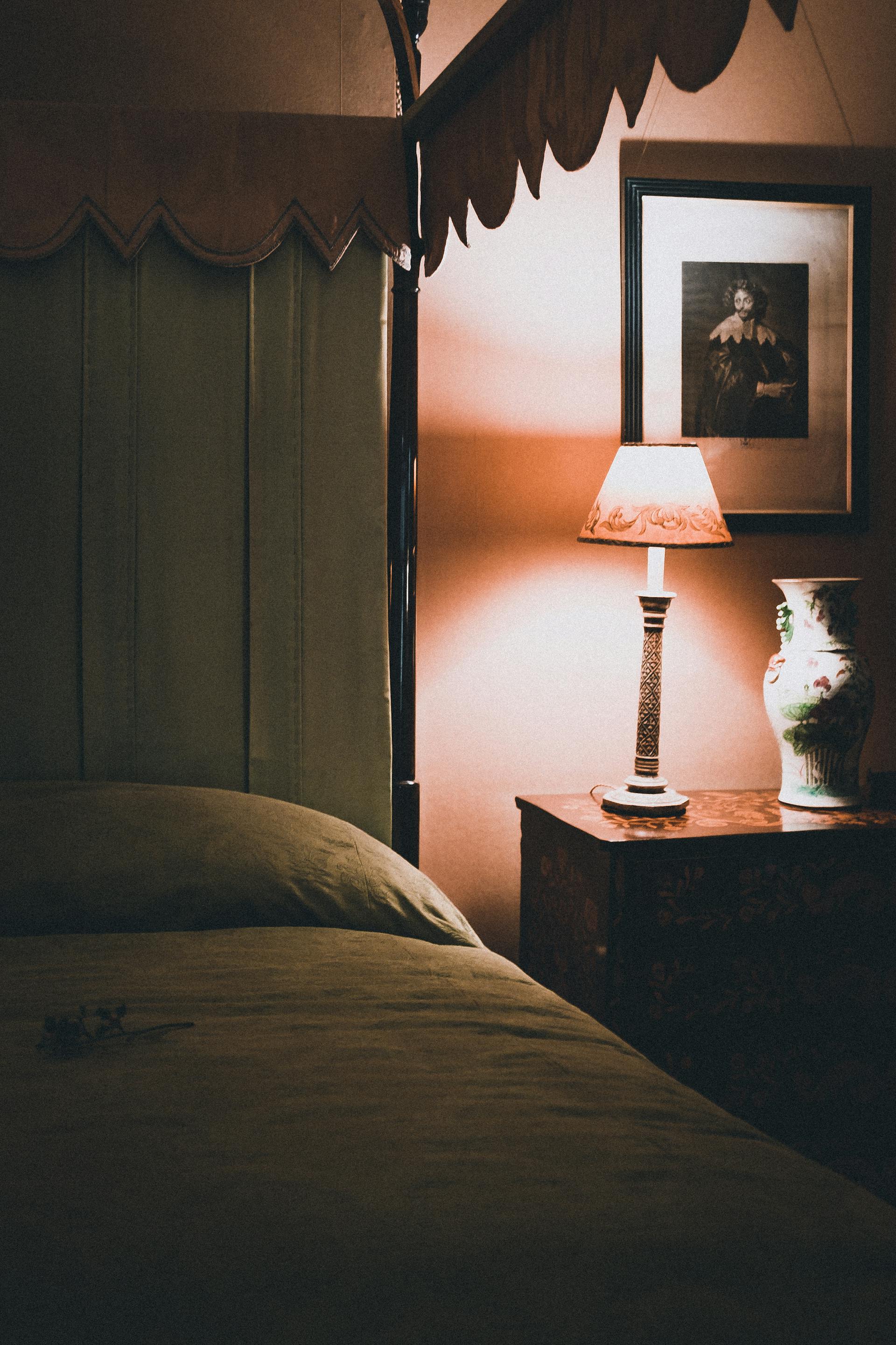 Gros plan sur une chambre à coucher faiblement éclairée par une lampe de table | Source : Pexels