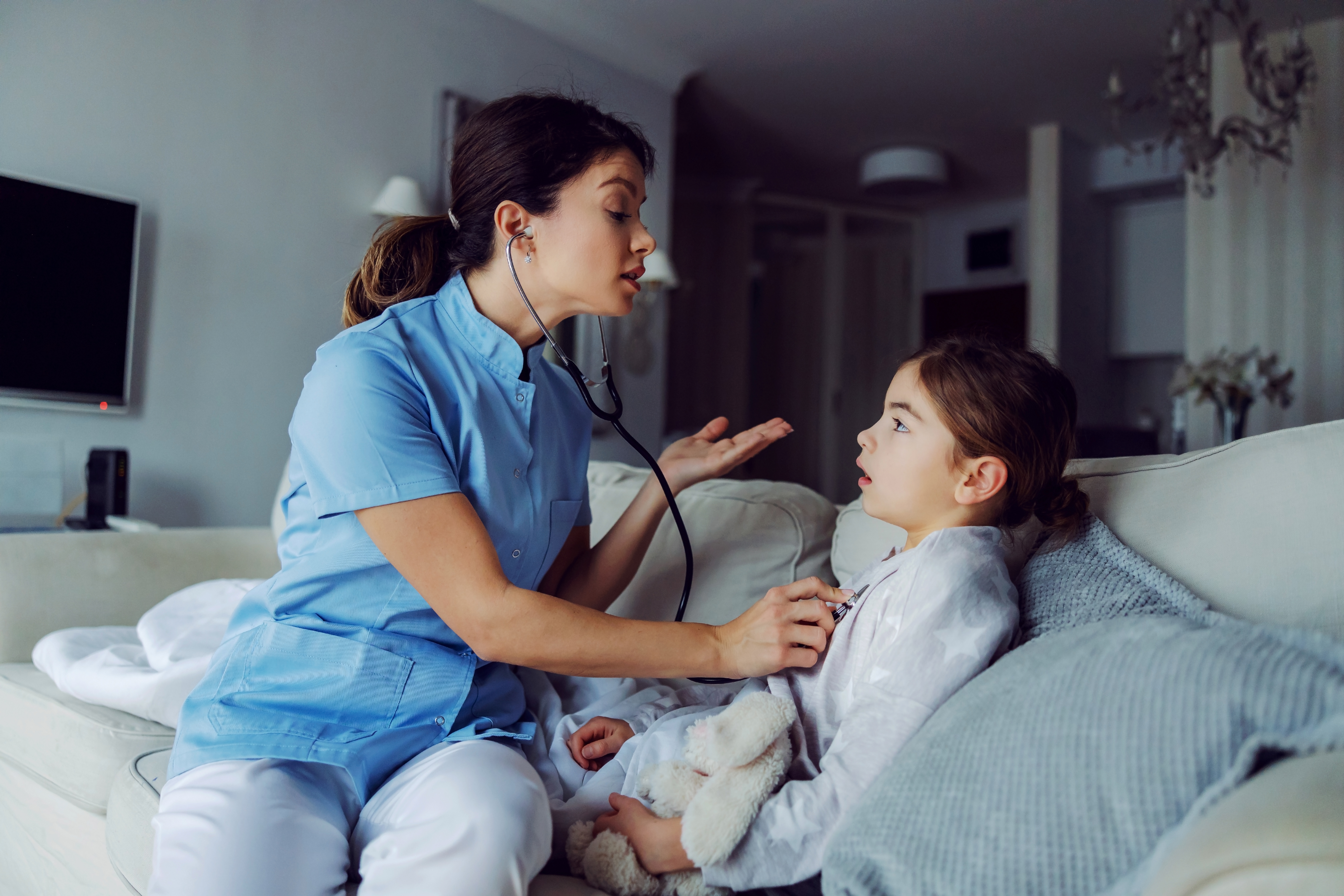 Médica sentada ao lado de menina e examinando os pulmões com estetoscópio |  Fonte: Shutterstock.com