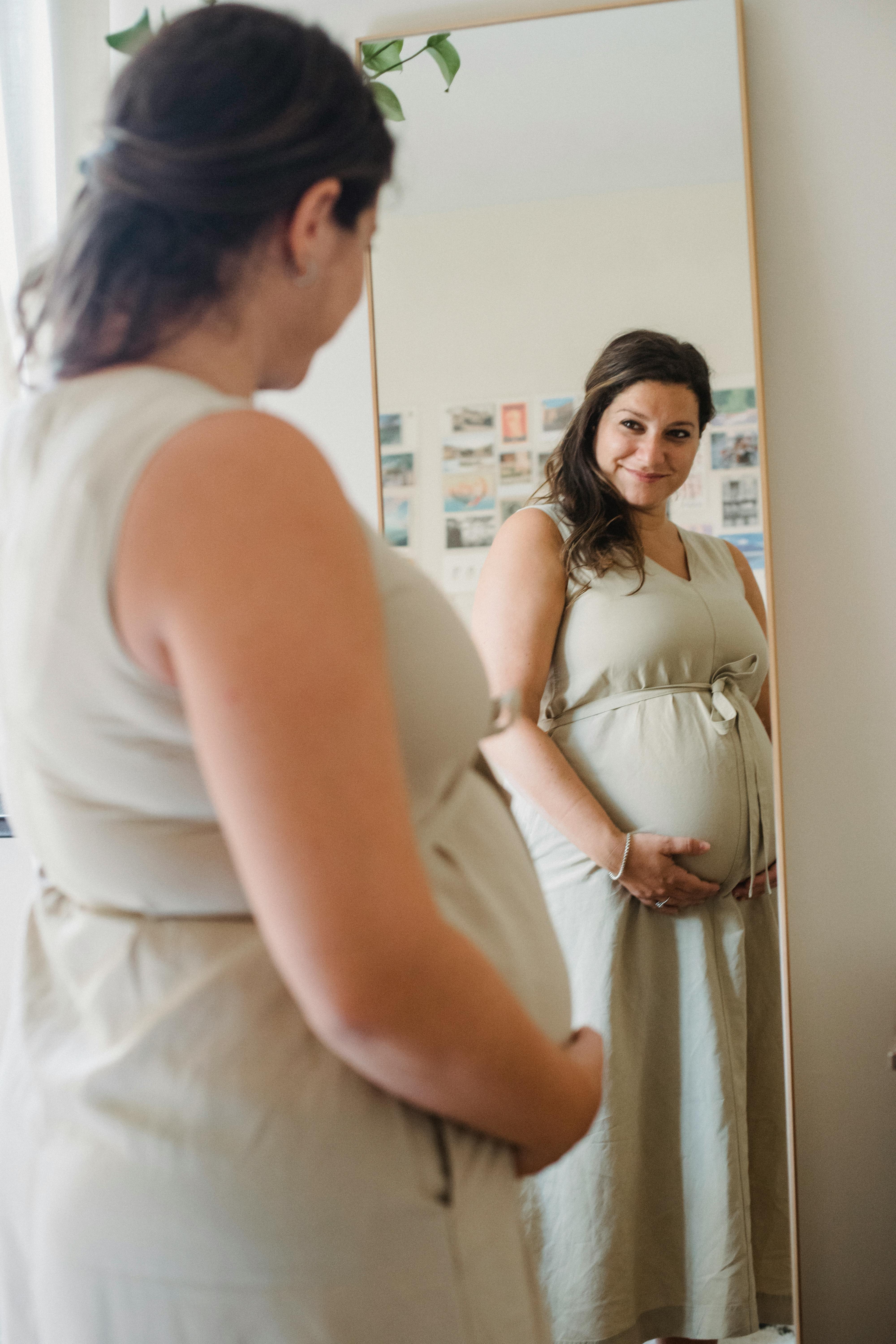 Une femme enceinte heureuse qui se regarde dans un miroir | Source : Pexels