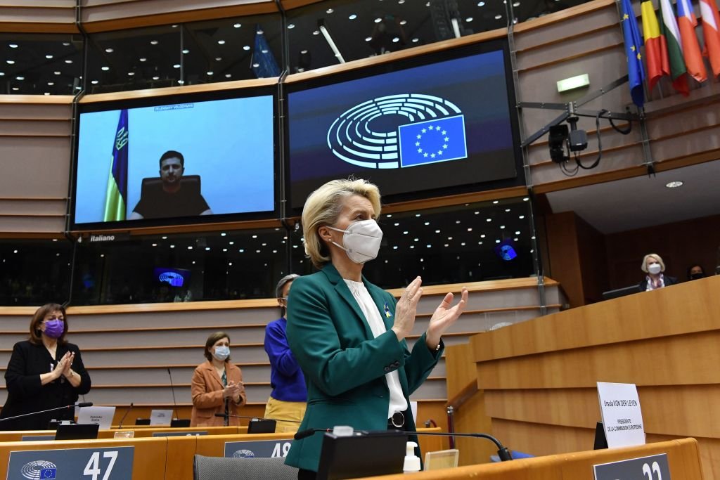 La présidente de la Commission européenne, Ursula von der Leyen (C), applaudit le président ukrainien Volodymyr Zelensky (L) qui apparaît sur un écran alors qu'il s'exprime lors d'une vidéoconférence lors d'une session plénière spéciale du Parlement européen axée sur l'invasion russe de l'Ukraine au siège de l'UE à Bruxelles, le 01 mars 2022. - La Commission européenne a ouvert la porte à l'adhésion de l'Ukraine à l'UE, mais ce n'est pas pour demain, malgré la demande de Kiev d'une procédure spéciale pour intégrer la zone "sans délai".ǀ Sources : Getty Images