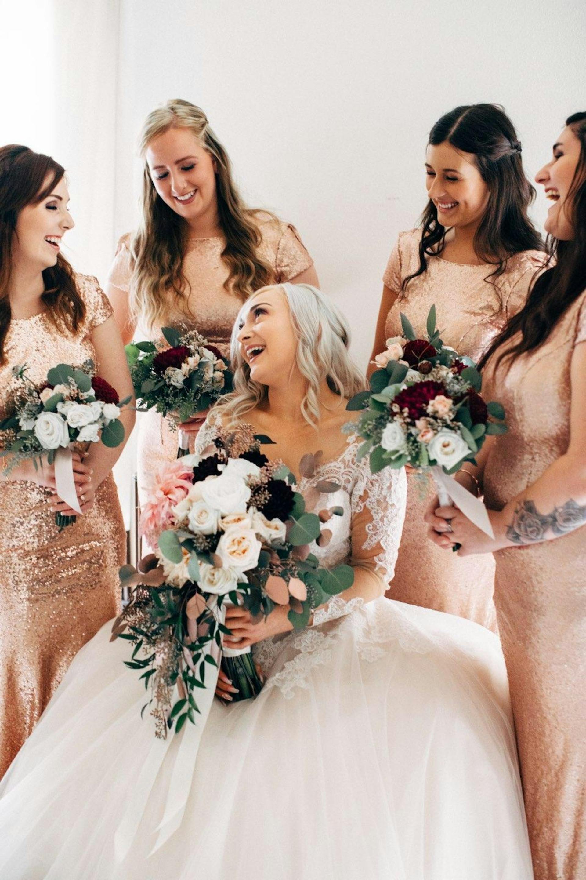 Une mariée heureuse et ses demoiselles d'honneur tenant des bouquets | Source : Pexels