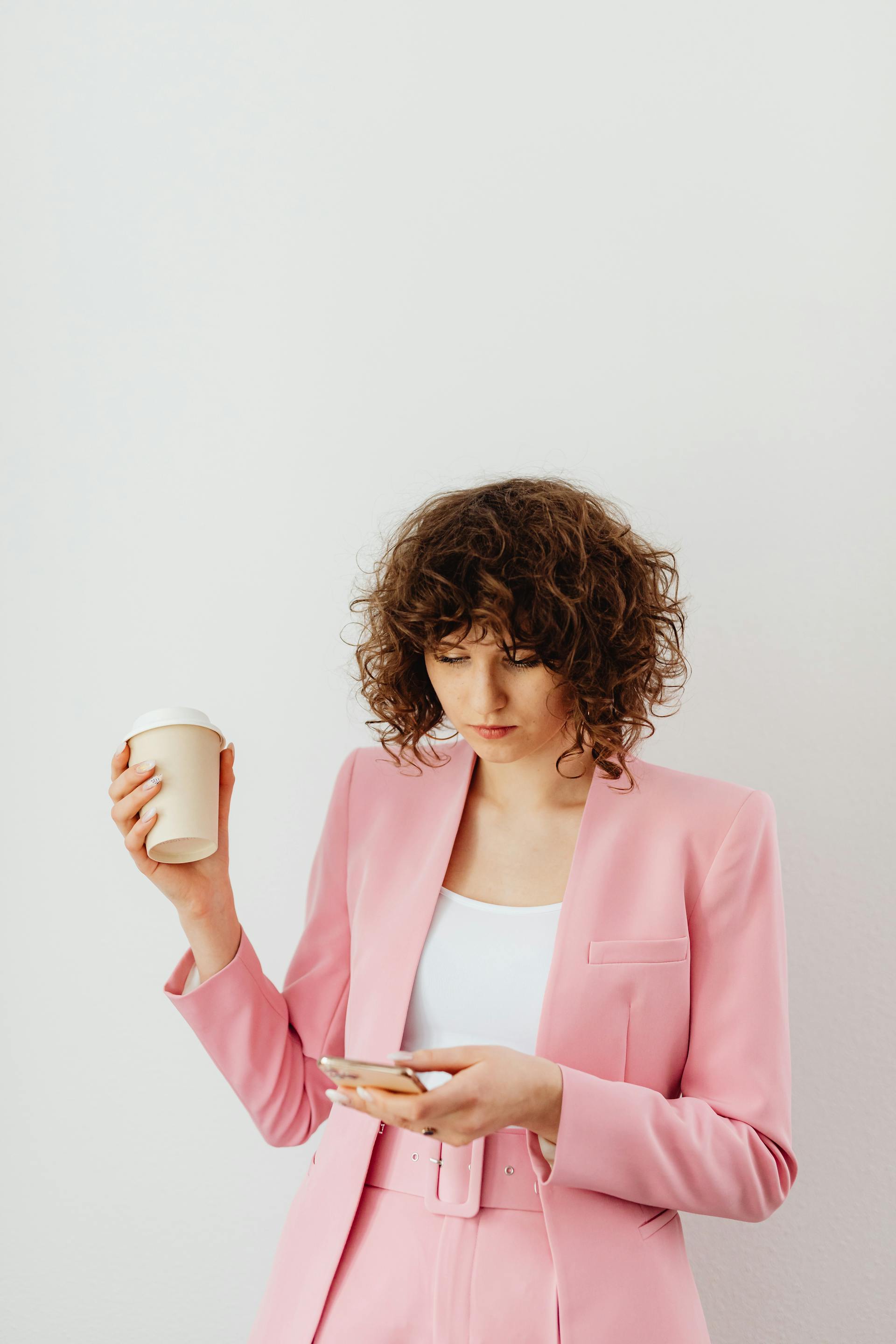 Une femme déterminée tenant un café et un téléphone | Source : Pexels