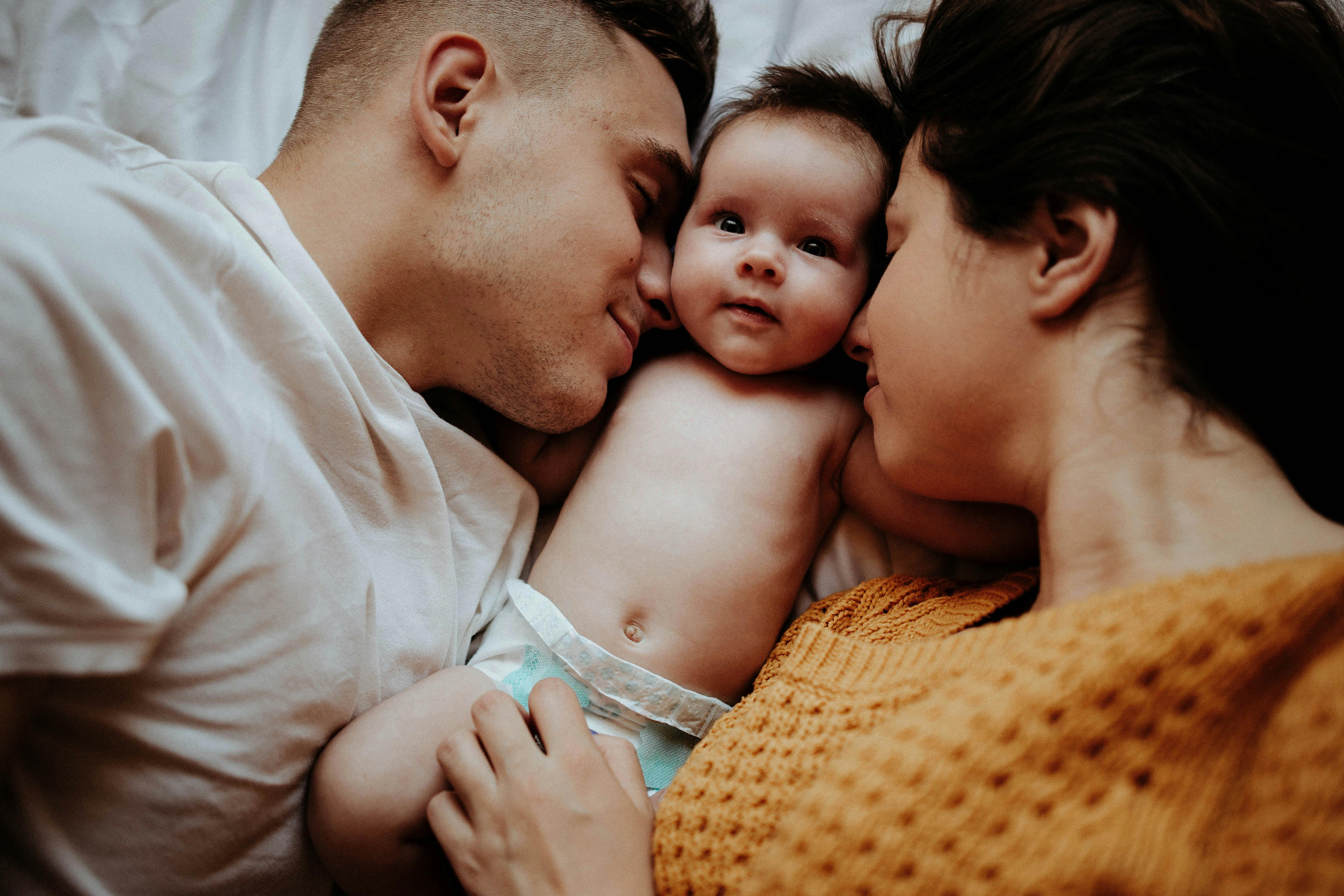 Un couple câlinant son bébé | Source : Pexels
