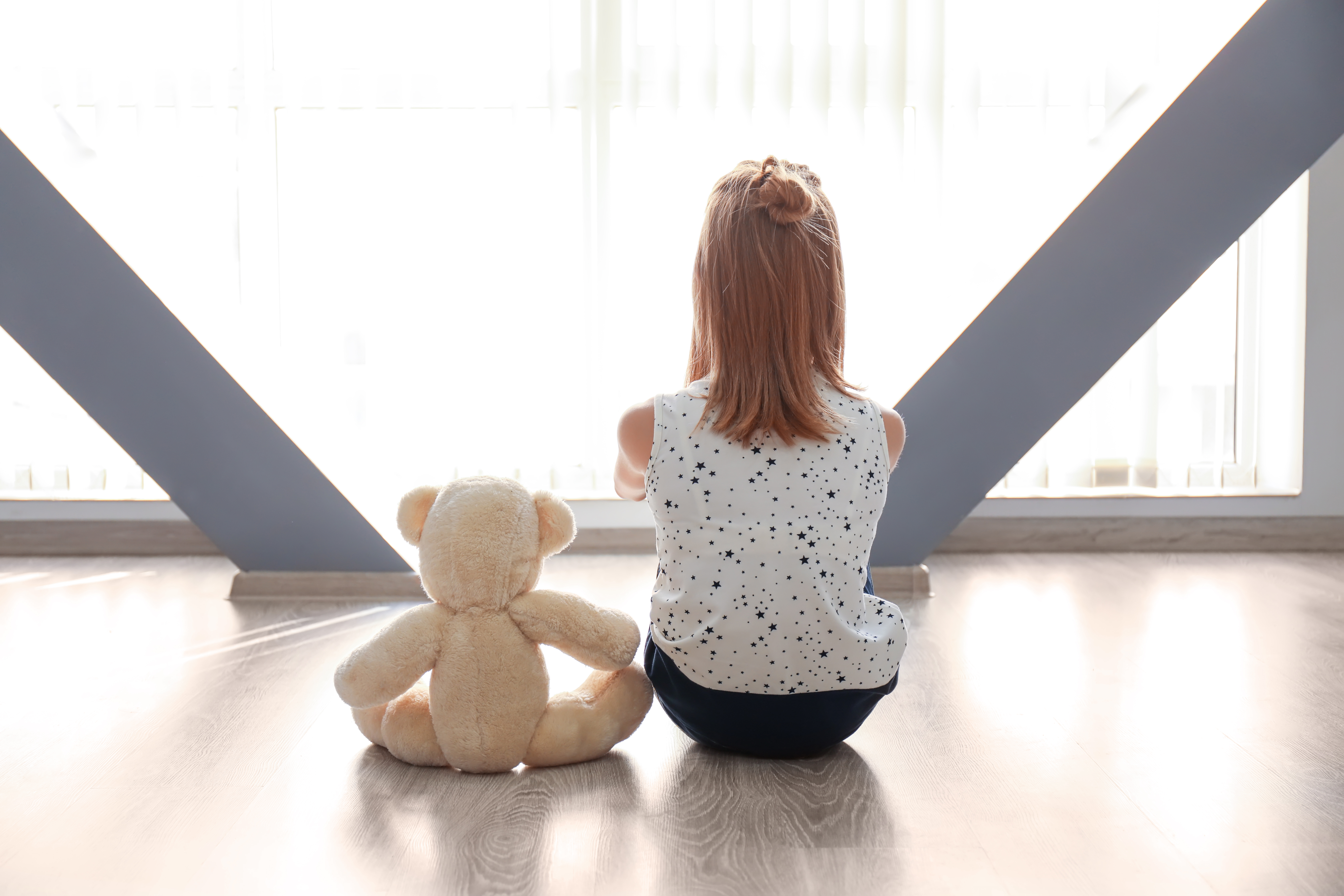 Une jeune fille assise seule sur le sol avec son ours en peluche | Source : Shutterstock