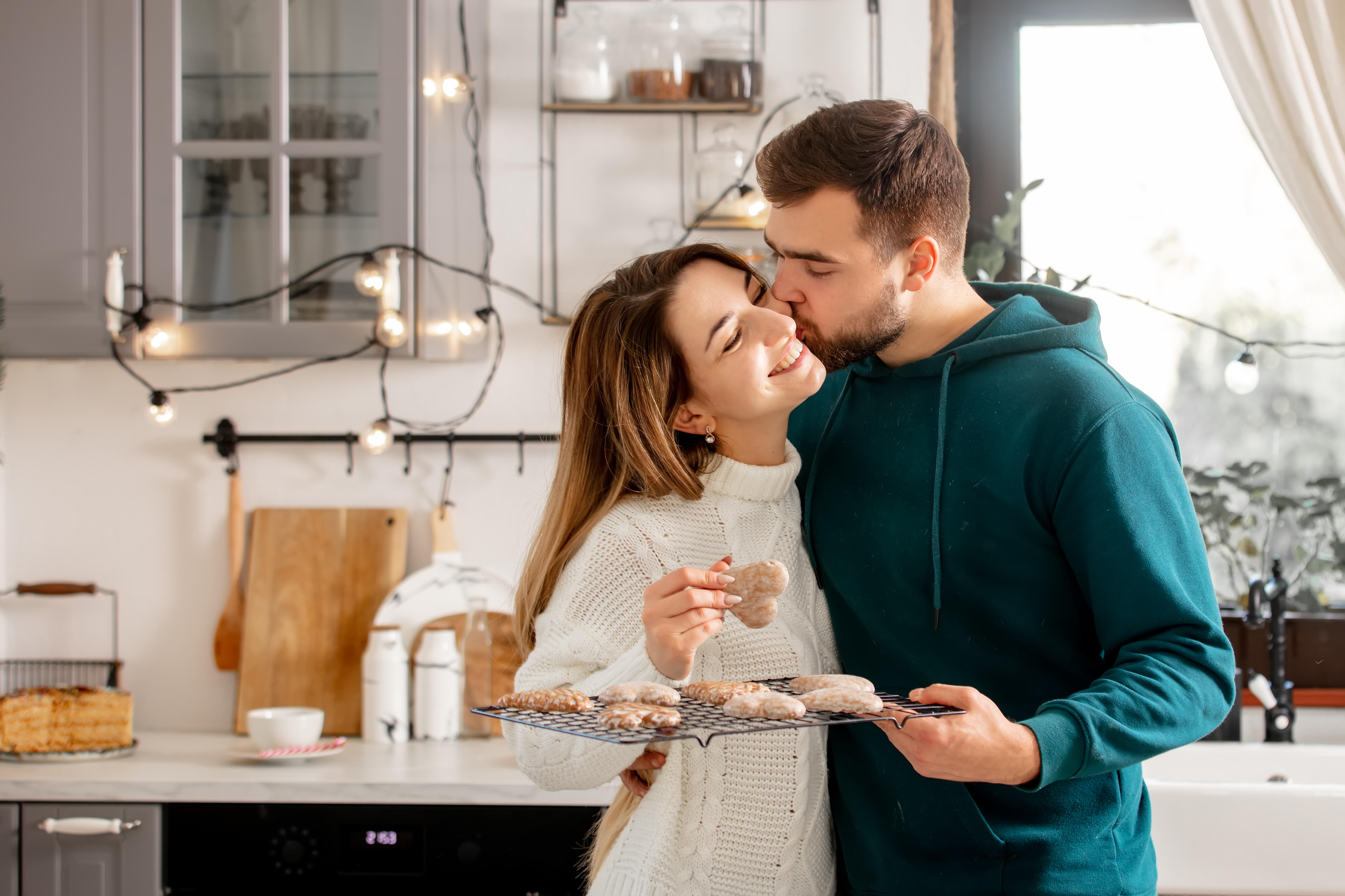 Un homme qui embrasse sa femme tout en préparant des biscuits à la maison | Source : Shutterstock