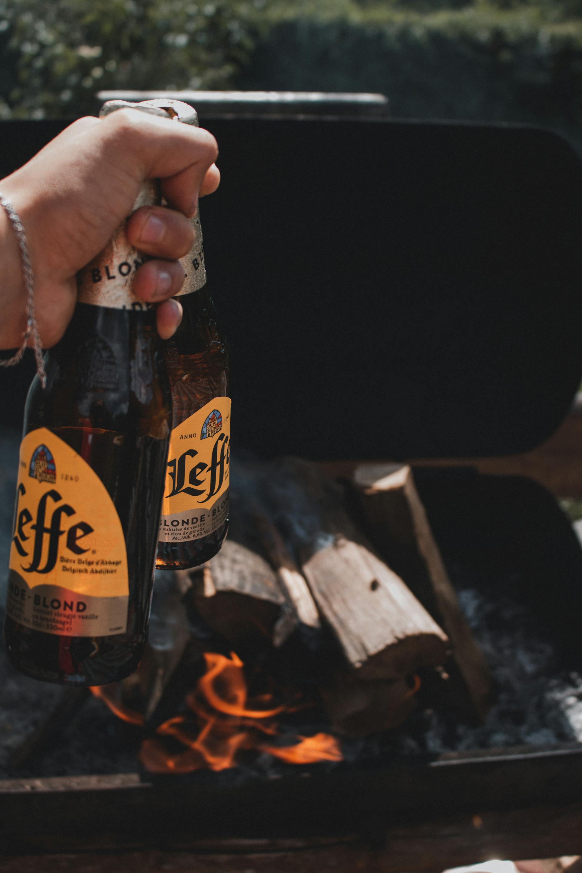 Une personne tenant une bière avec du bois de chauffage en arrière-plan | Source : Pexels