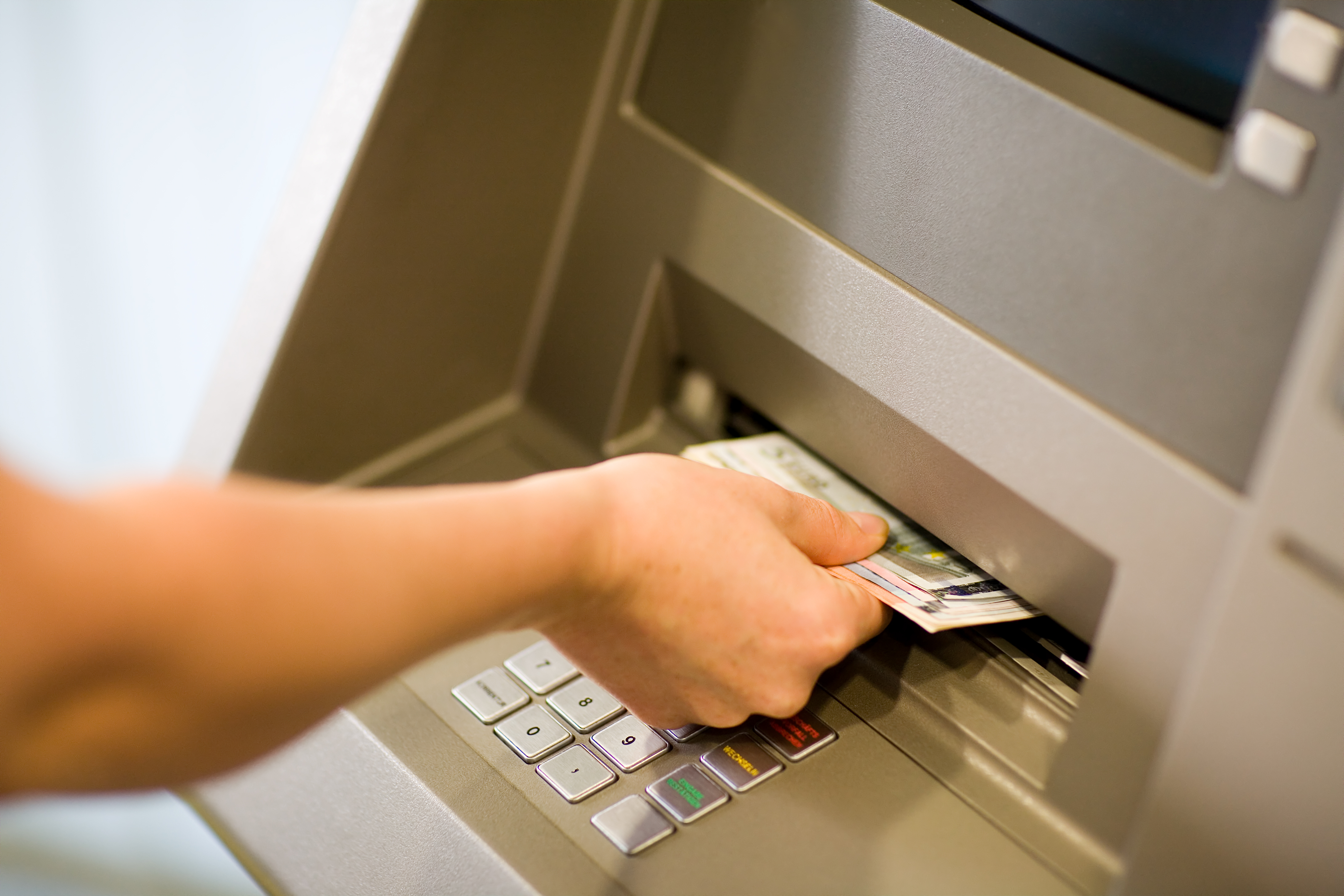 Une personne qui récupère de l'argent à un distributeur automatique. | Source : Shutterstock