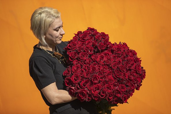 Une femme qui porte un énorme bouquet de roses rouge.| Photo : Getty Images