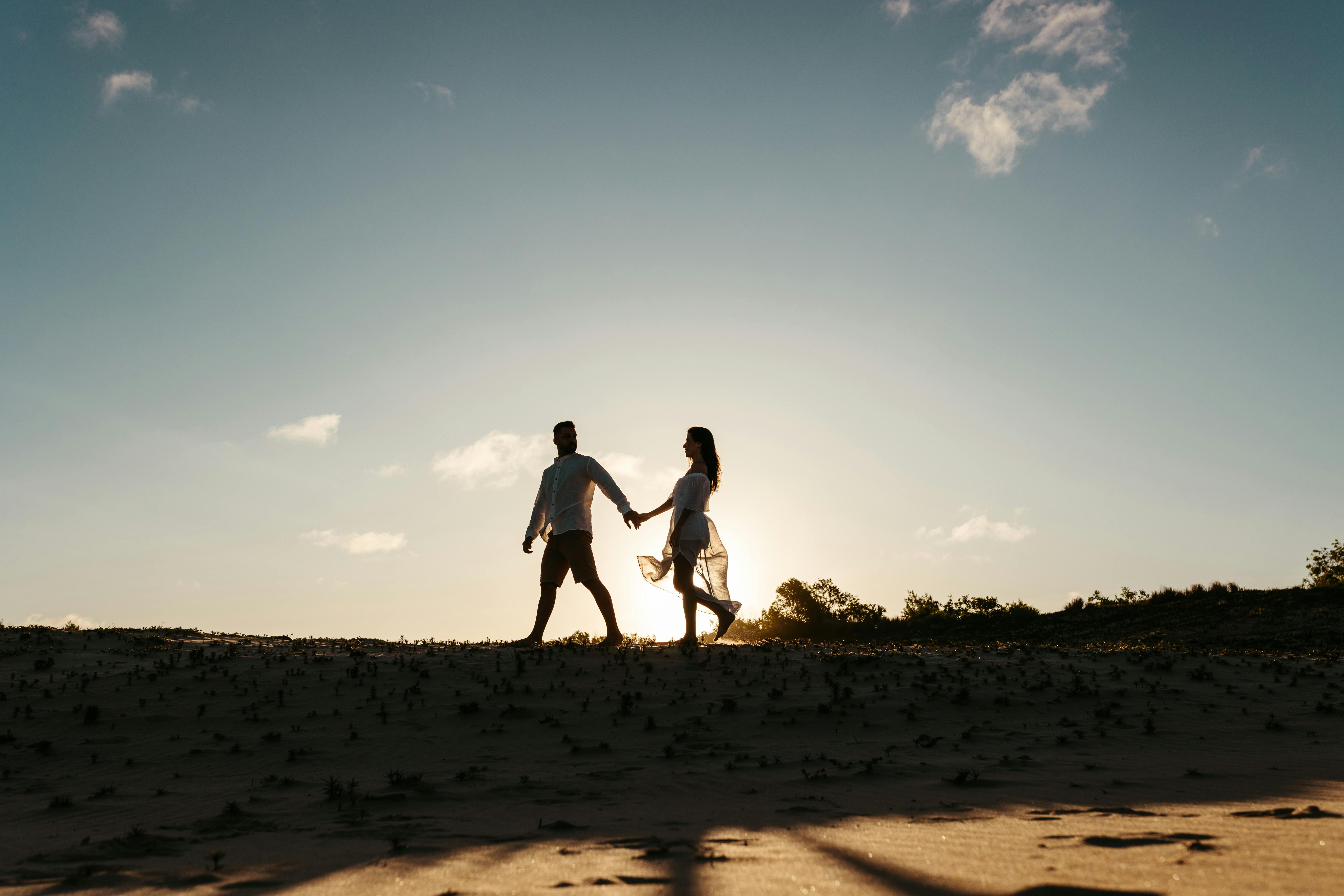 Homme et femme marchant main dans la main en plein air | Source : Pexels