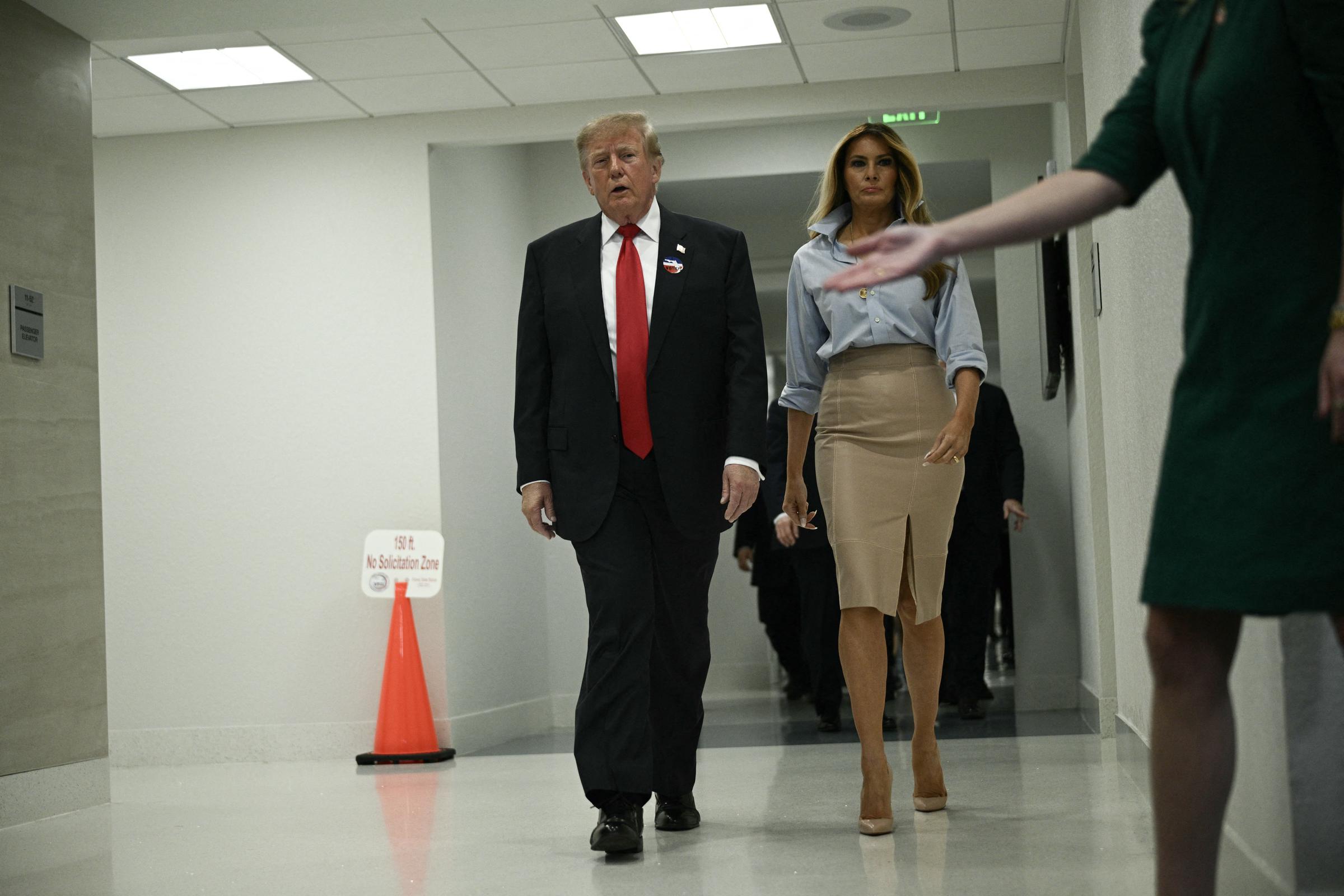 Alors qu'ils avancent dans un couloir intérieur après avoir voté, la Première Dame attire tous les regards dans son haut à col et manches retroussées et sa jupe fendue sur le devant. Elle complète cette tenue aux couleurs douces avec des talons aiguilles nude vertigineux qui donnent à chacun de ses pas une touche audacieuse et tranchante comme une lame de rasoir.