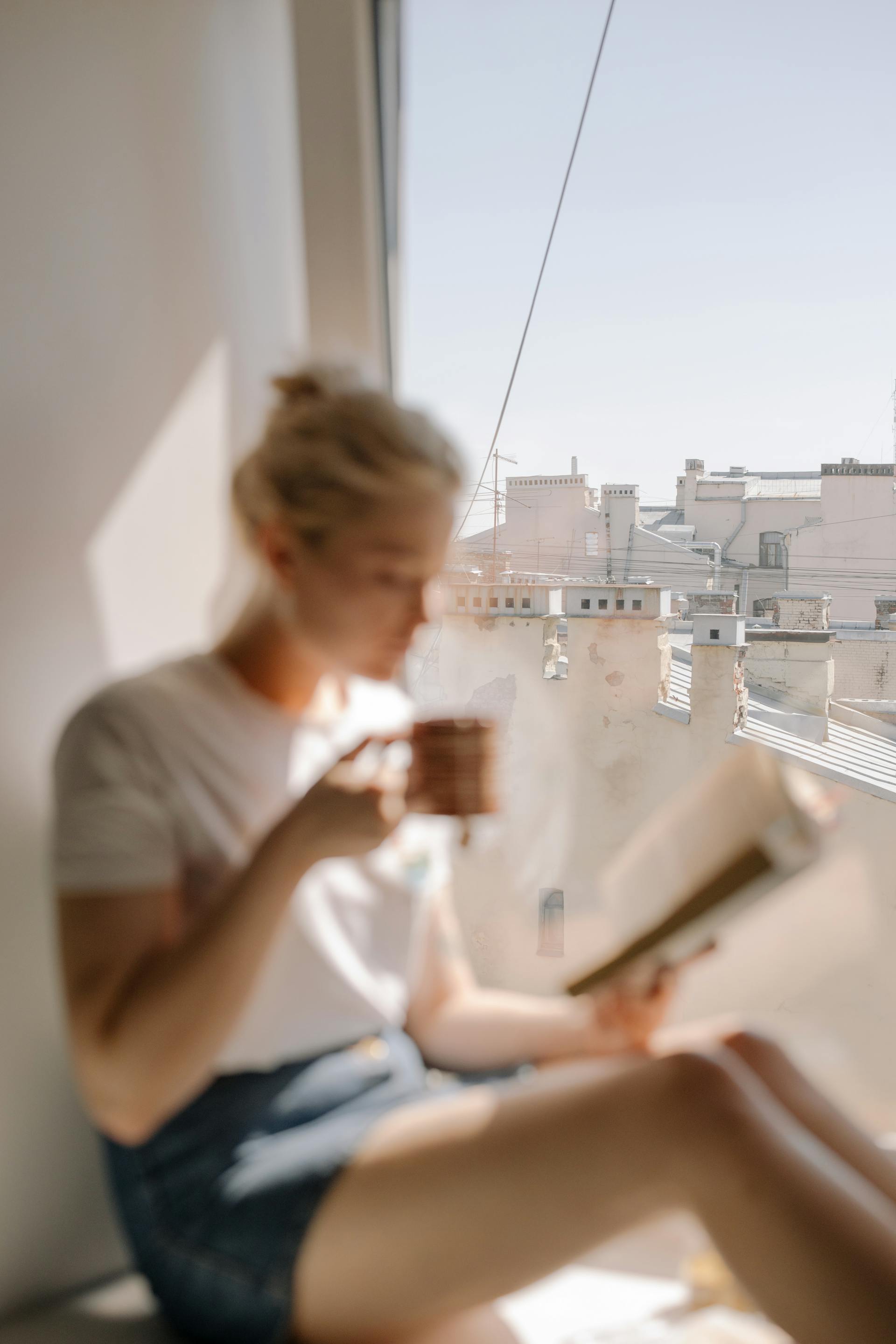 Une femme boit un café près de la fenêtre d'un appartement | Source : Pexels