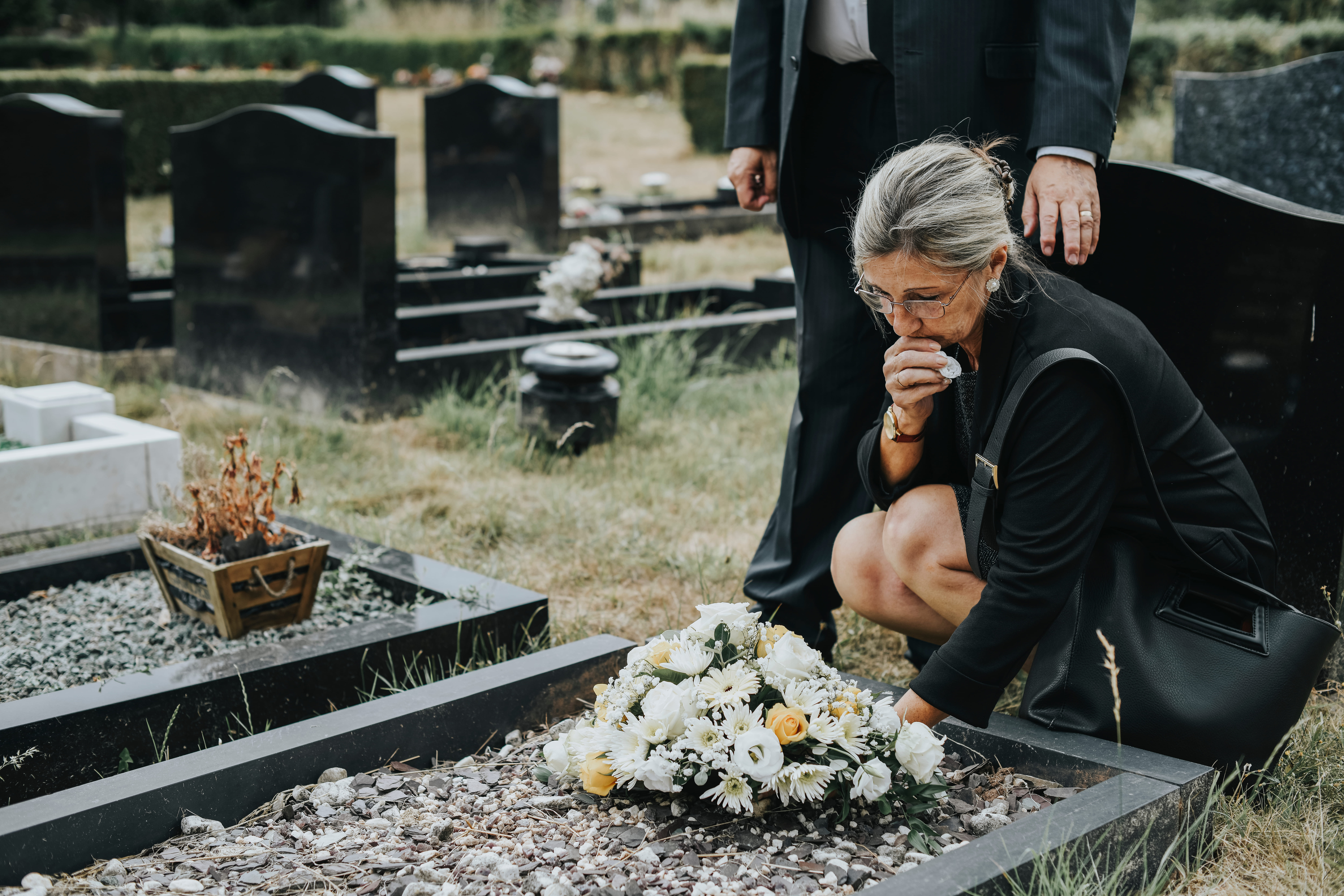 Femme âgée déposant des fleurs sur une tombe | Source : Shutterstock