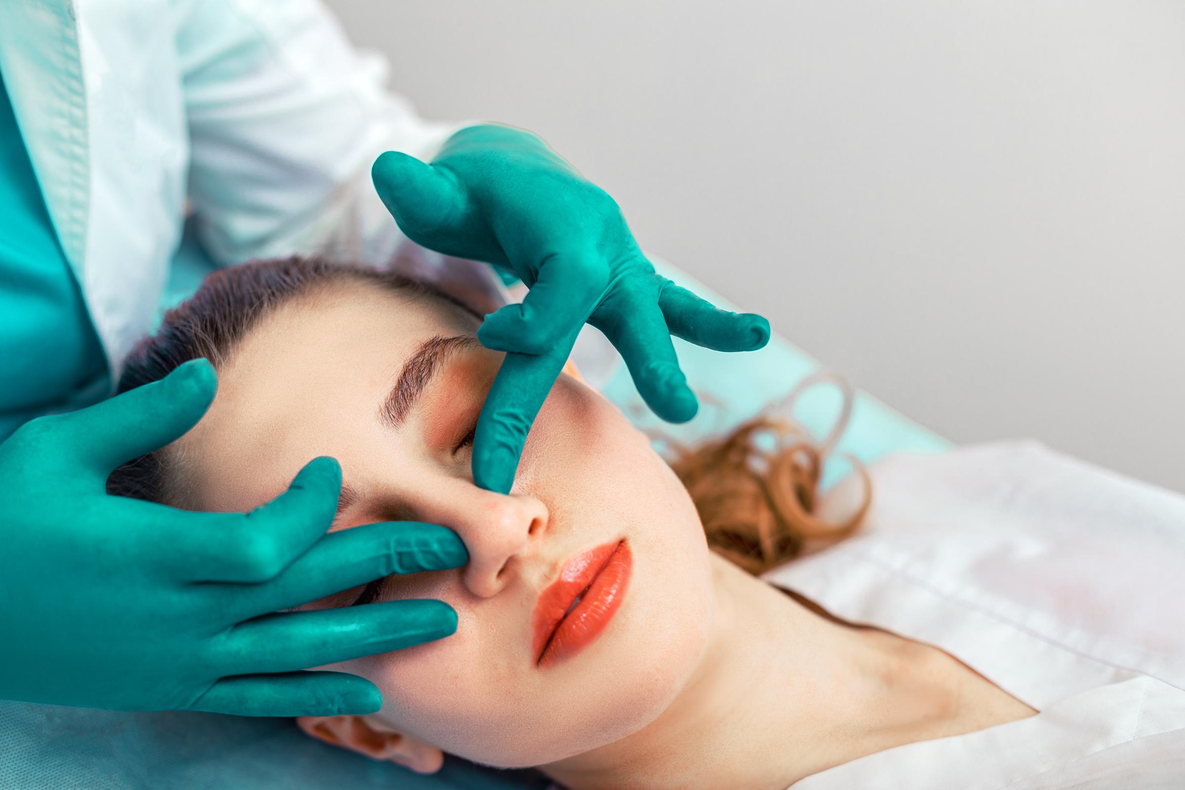 Les mains du chirurgien touchent le nez du patient | Source : Getty images