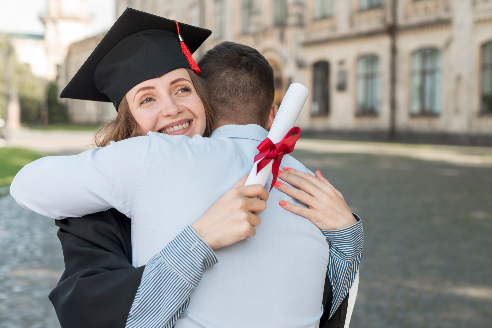 Une femme heureuse diplômée de l'université embrassée par un homme | Source : Pexels
