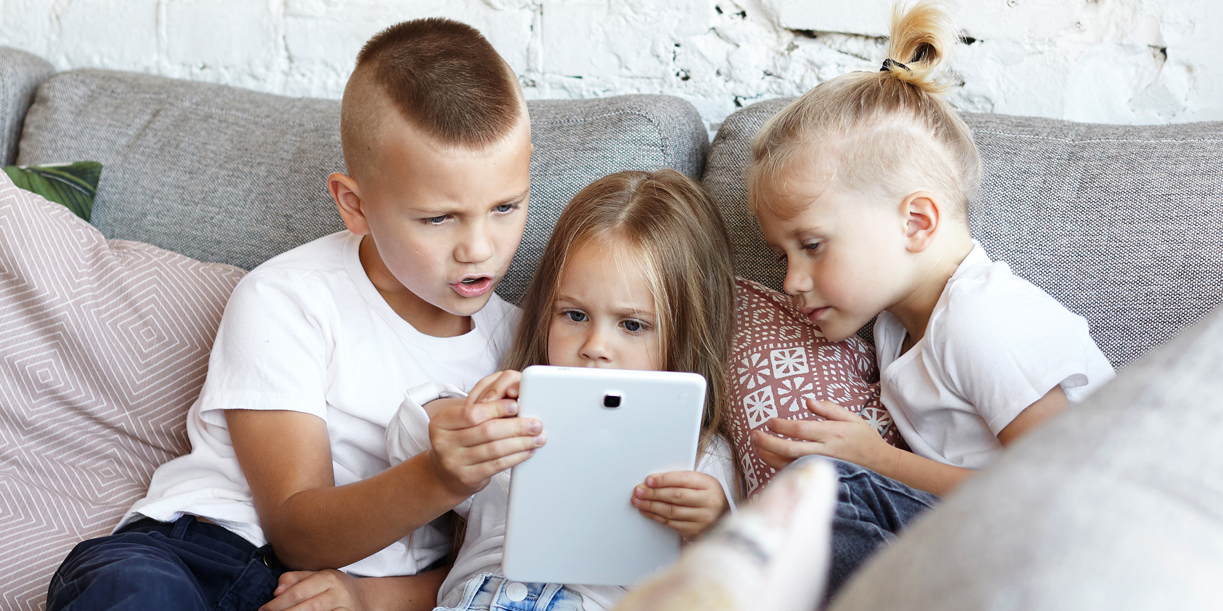 Trois enfants assis sur un canapé | Source : Shutterstock