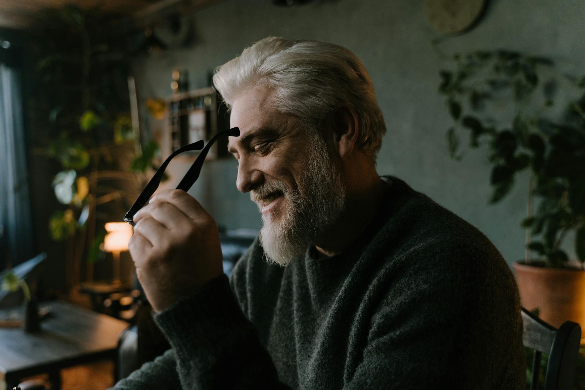 Un homme plus âgé tenant ses lunettes et riant | Source : Pexels