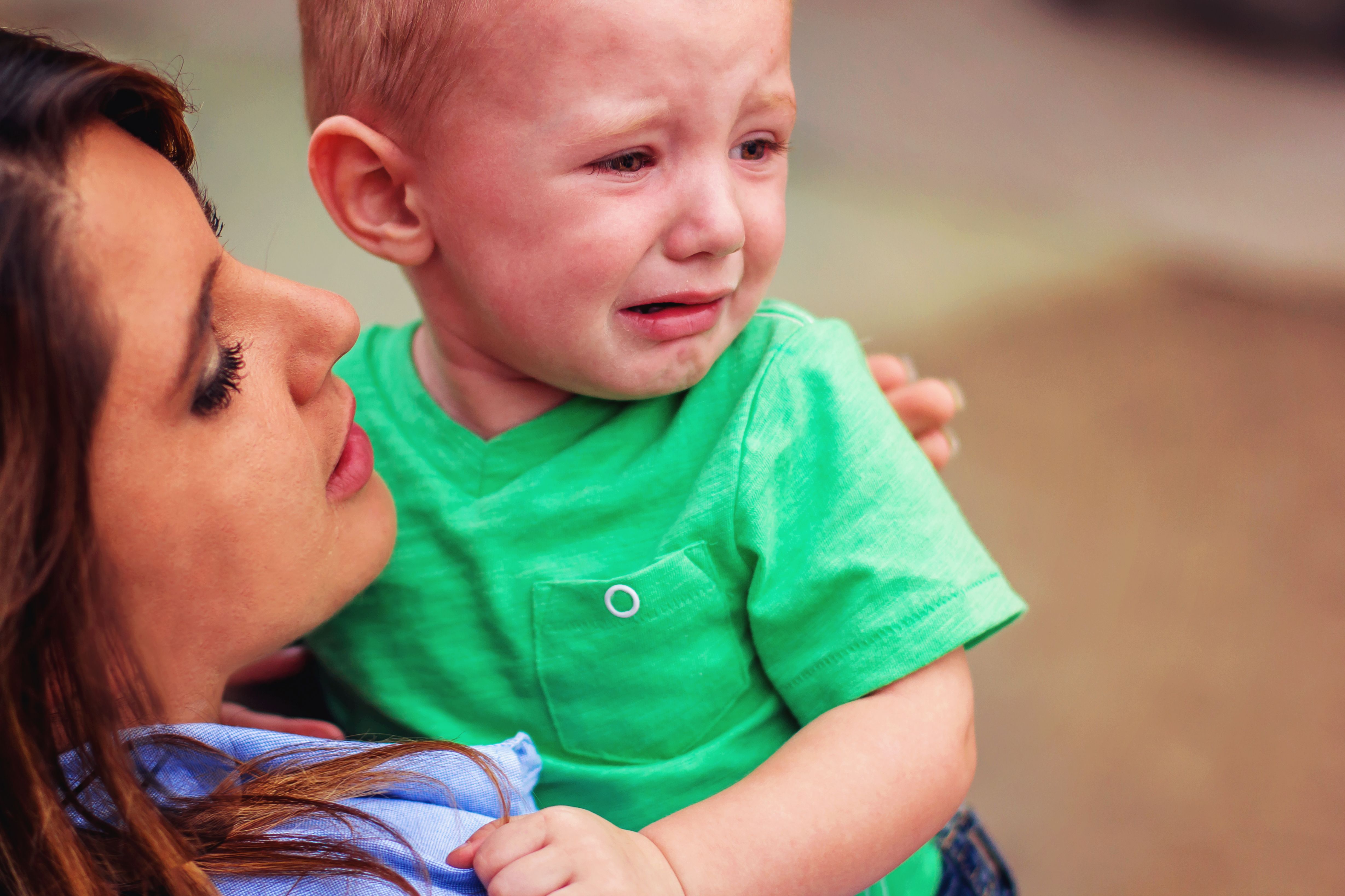 Un enfant en bas âge qui pleure dans les bras de sa mère. | Source : Shutterstock