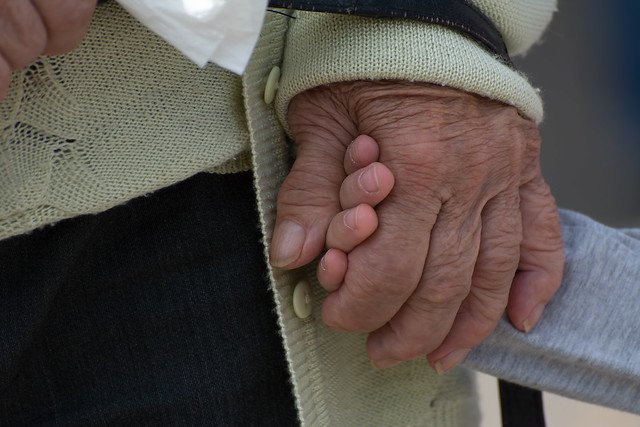 Une personne âgée tenant la main d'un enfant. l Source: Flickr