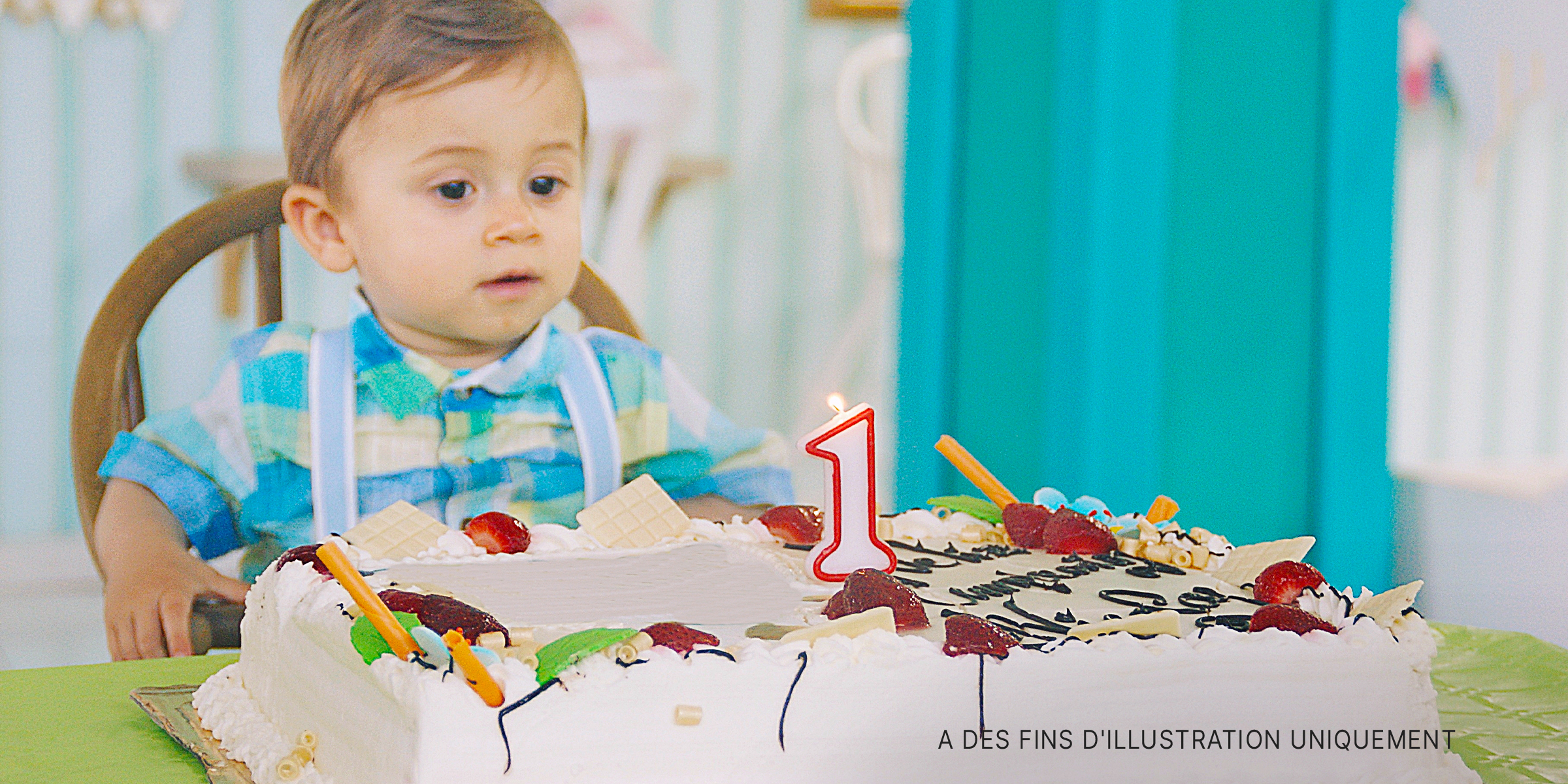Un enfant en bas âge assis à une table, prêt à souffler une bougie sur son gâteau d'anniversaire | Source : Getty Images