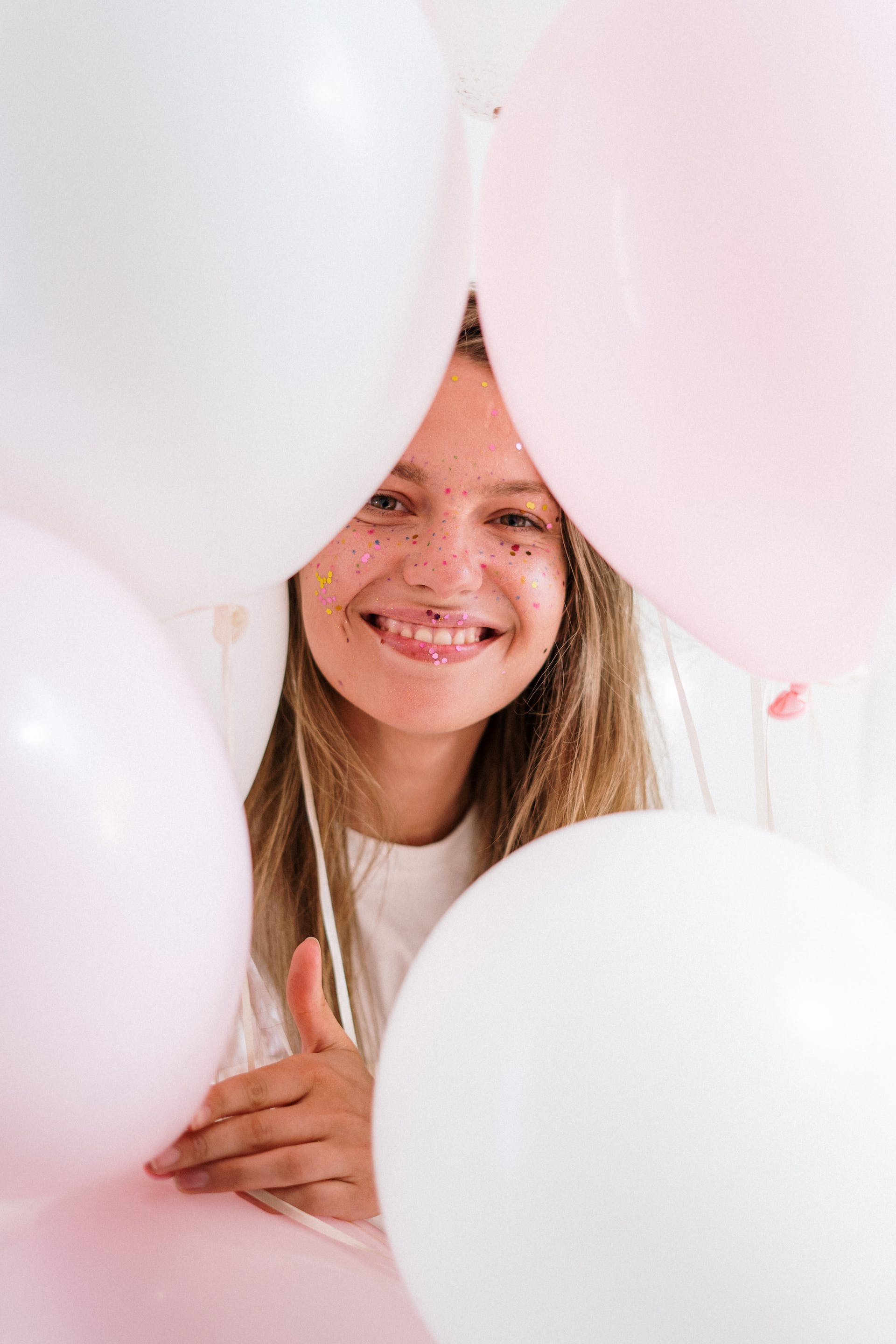 Une jeune fille sourit en tenant des ballons | Source : Pexels