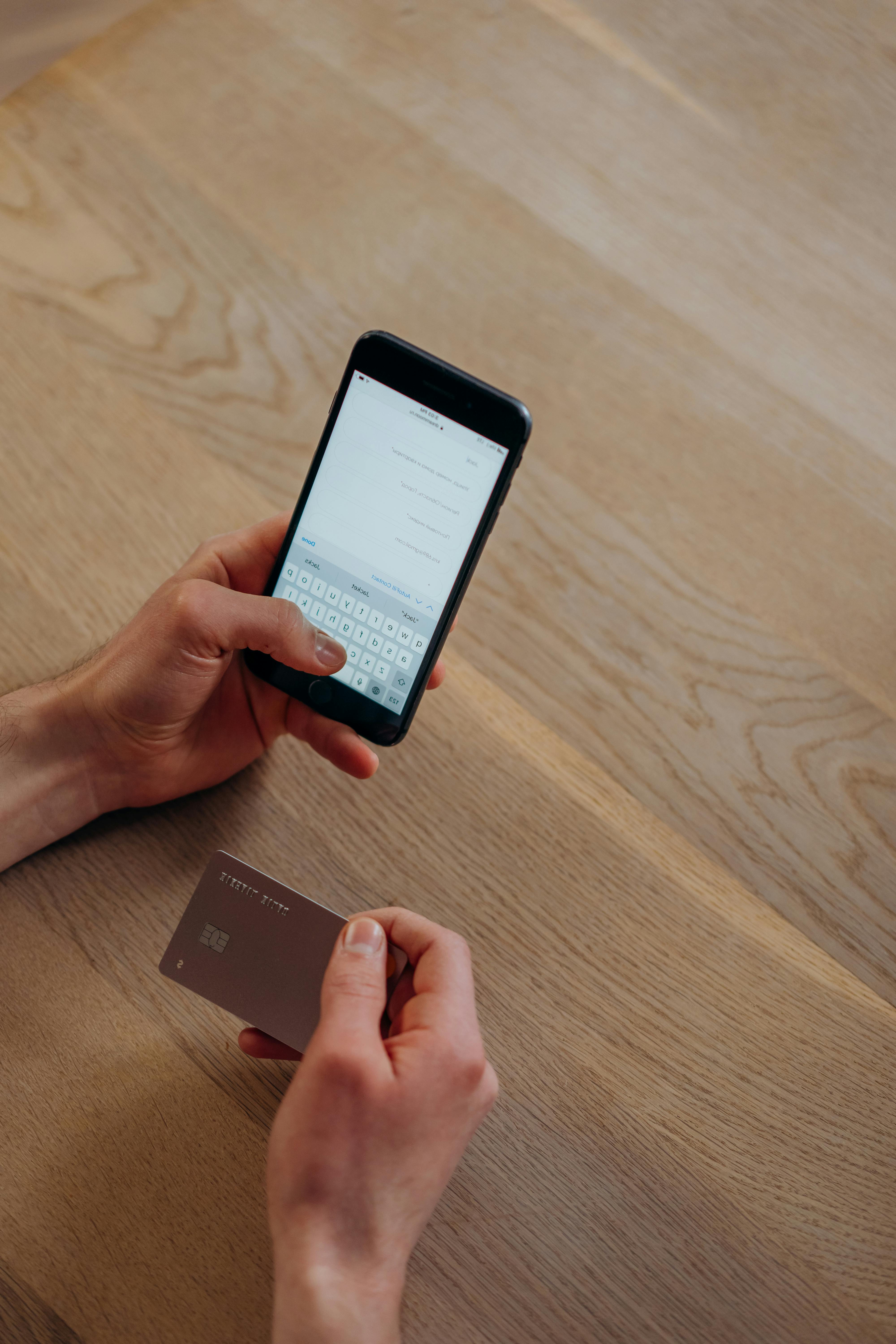 Une personne envoyant un texto tout en tenant une carte de crédit | Source : Pexels