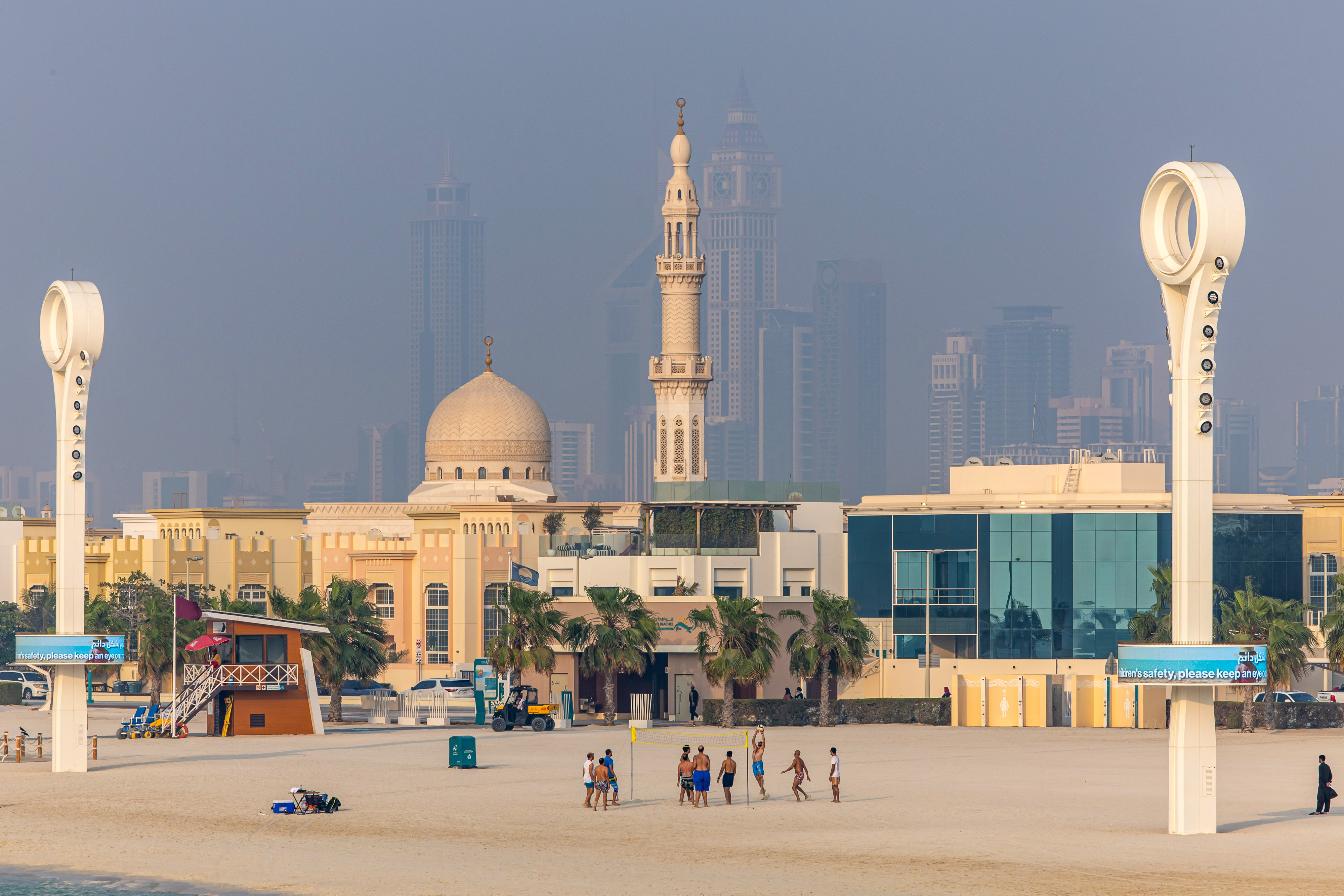 Des gens jouent au volley-ball, avec en toile de fond des propriétés résidentielles et commerciales dans le quartier de Jumeirah Beach à Dubaï, aux Émirats arabes unis, le 25 août 2023 | Source : Getty Images