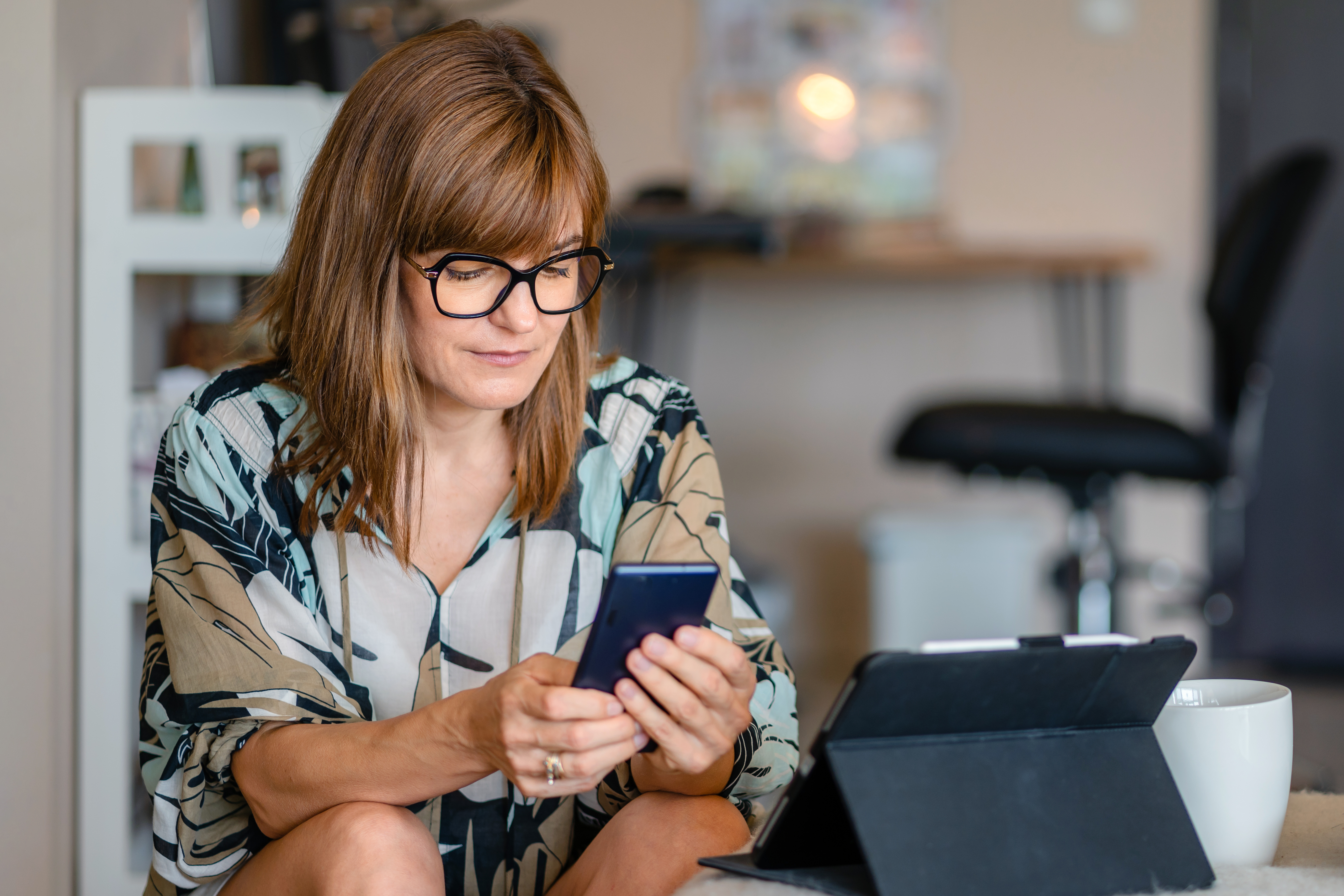 Femme d'affaires sérieuse et célibataire utilisant son téléphone à la maison | Source : Getty Images