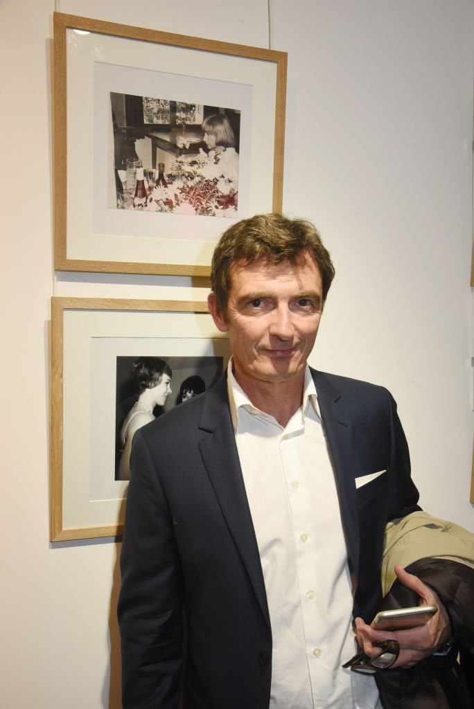 Denis Westhoff pose avec un portrait de sa mère écrivain Françoise Sagan (ci-dessus) pendant l'exposition "La Femme dans Le Siecle" et le cocktail de remise des prix à la Galerie FRM le 14 novembre 2017 à Paris, France. | Photo : Getty Images